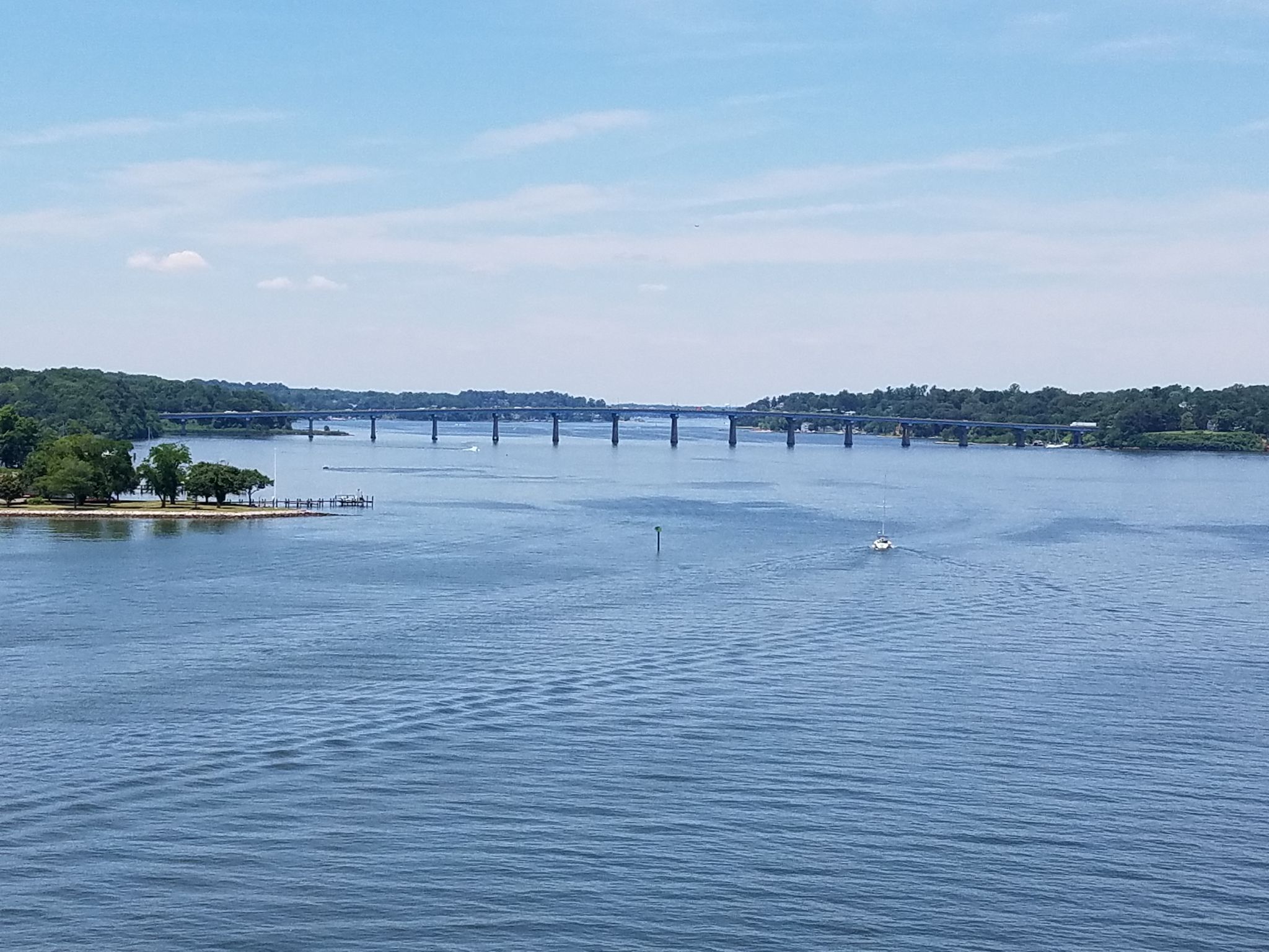 Wide river with a distant bridge, treeline, and small boat under blue sky. - Baltimore & Annapolis and BWI Trail Loop