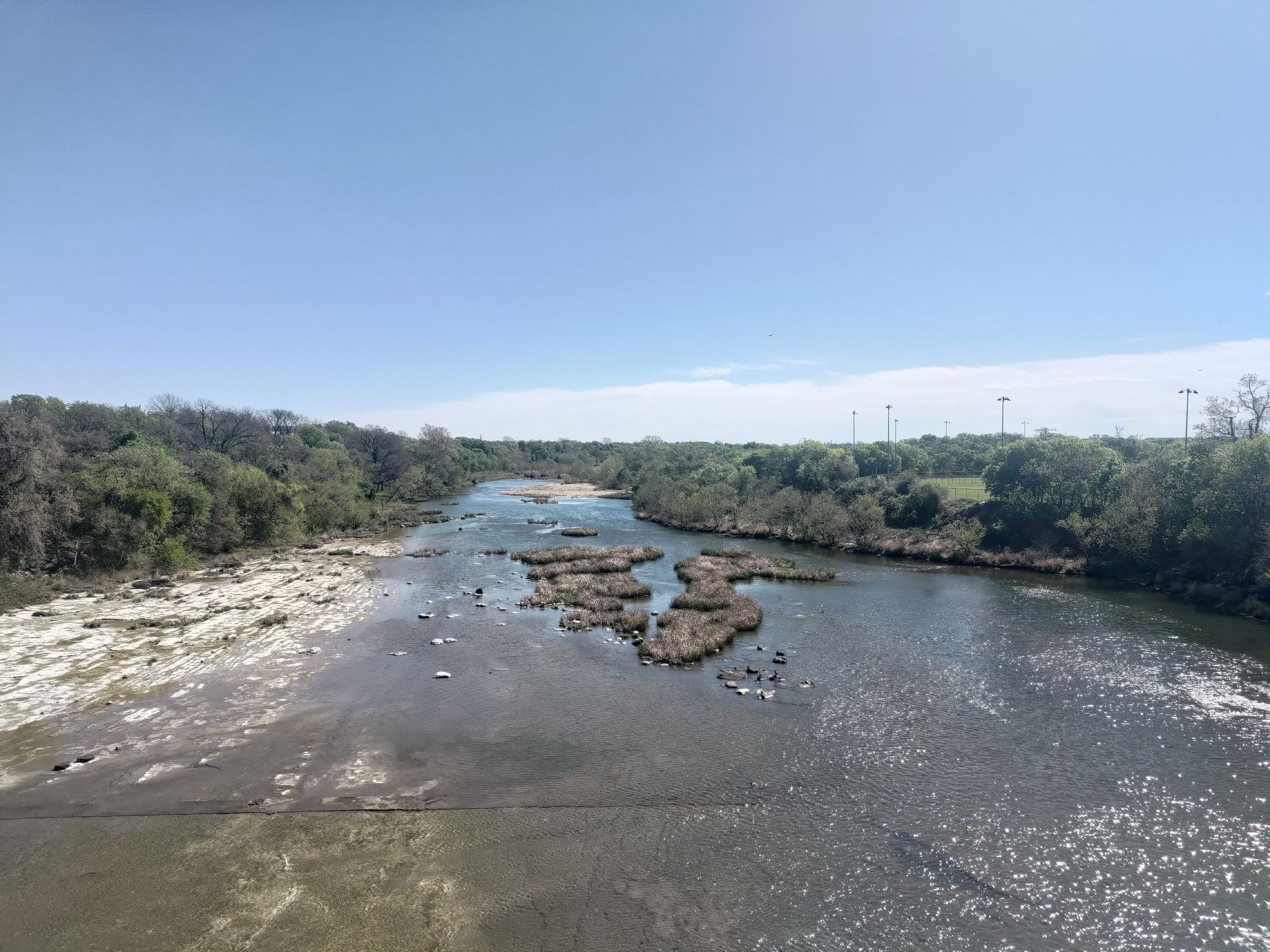 Wide river with rocky banks, green trees, and islands under a clear sky. - Violet Crown MJ's 4th of July Party loop