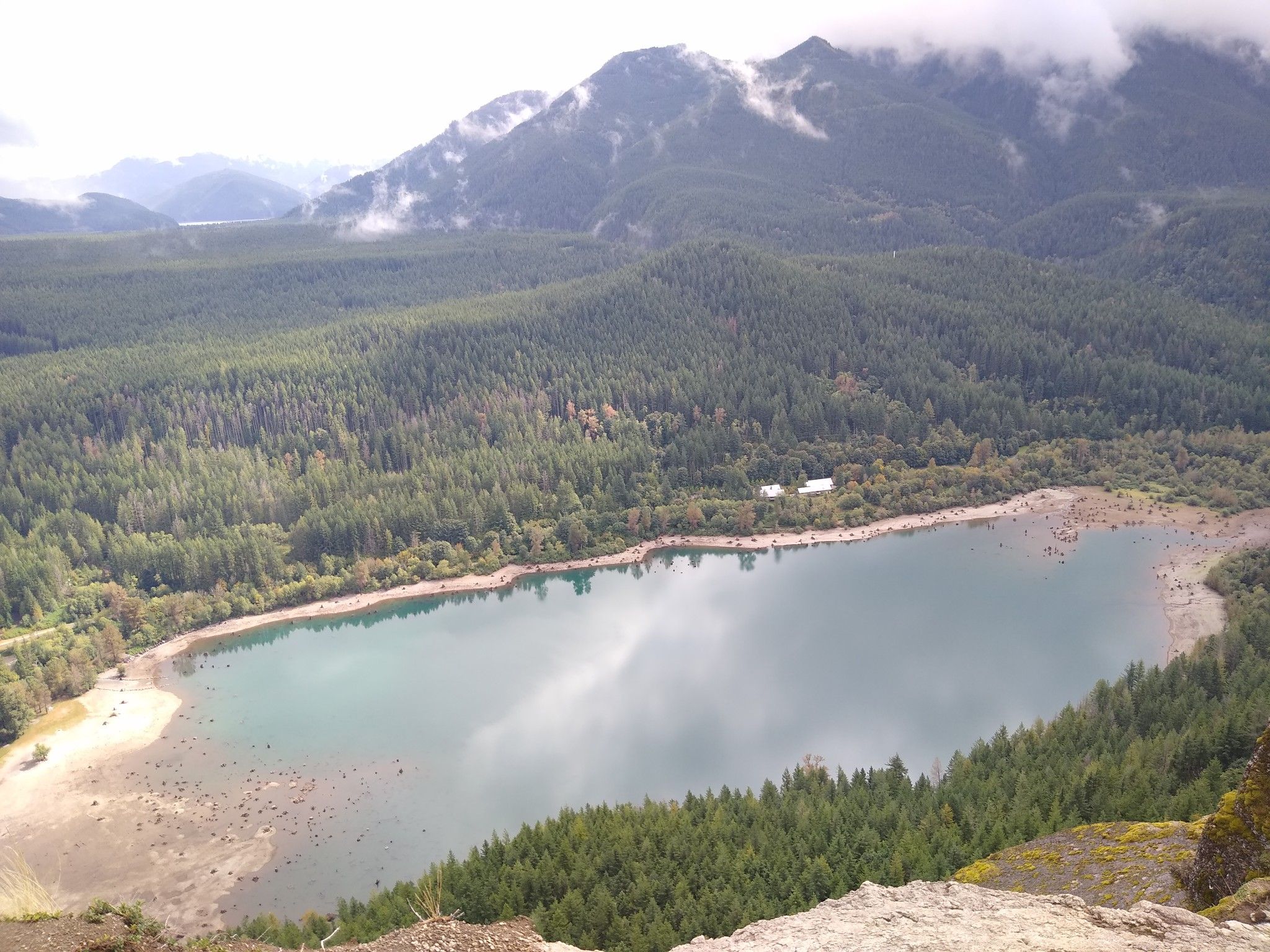 Overcast aerial view of a lake with sandy shores, surrounded by forest. - Rattlesnake Ledge Trail – Rattlesnake Lake loop from Wilderness Rim