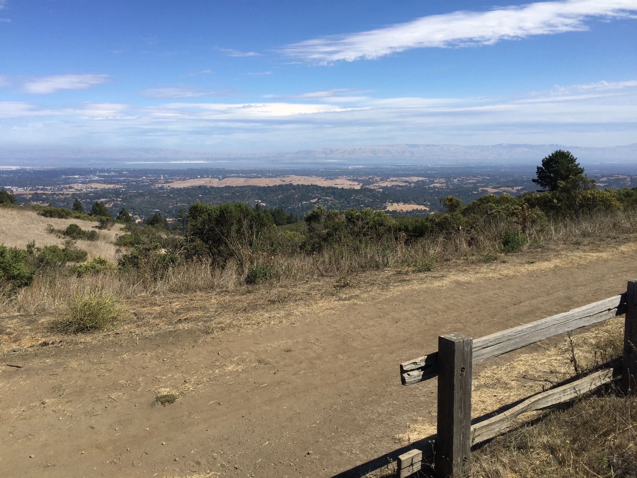 Dirt path and wooden fence overlooking a vast valley under a blue sky. - Windy Hill Summit loop from Portola Valley