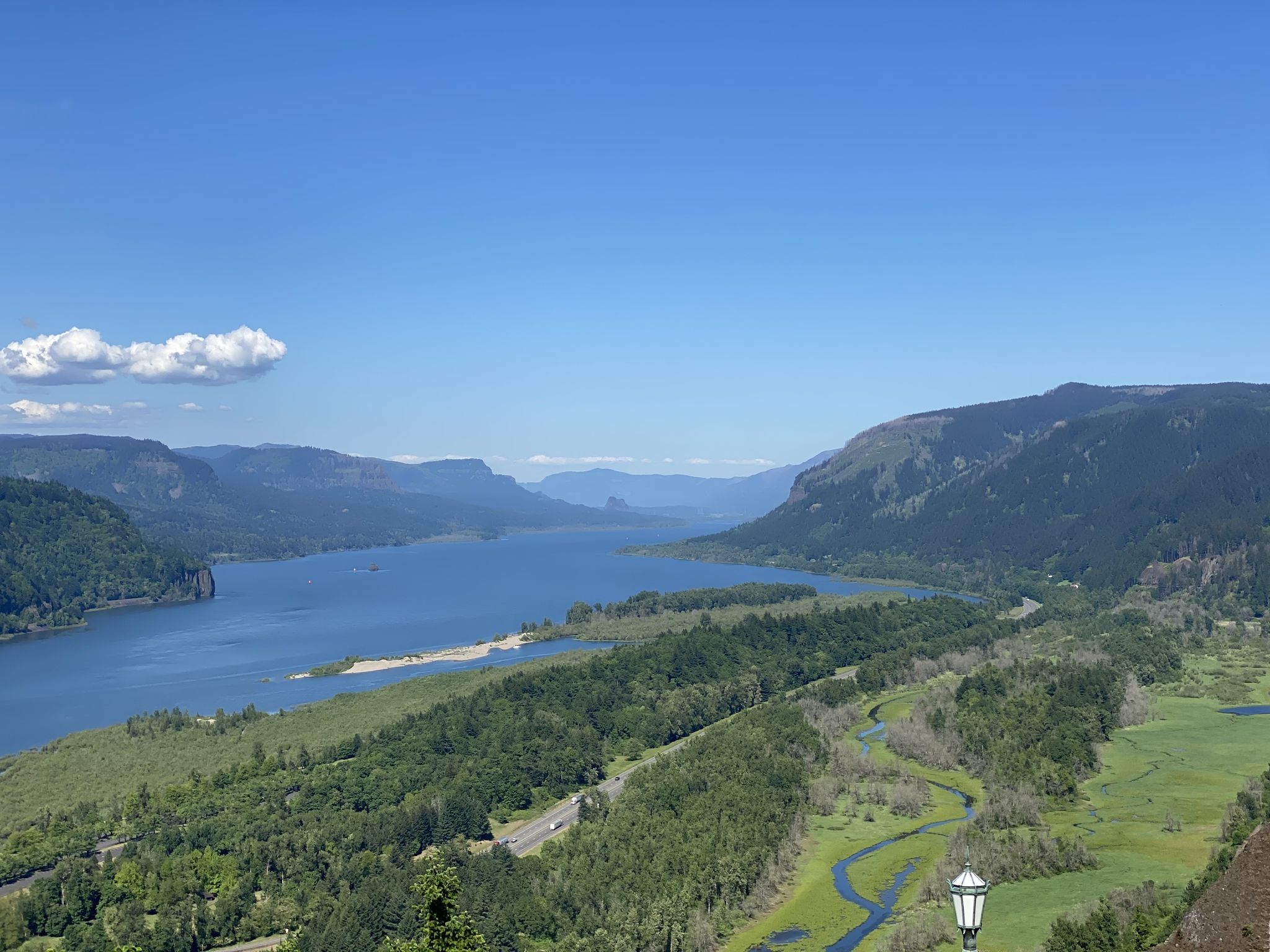 Wide river winding through green forested mountains under a bright blue sky. - Larch Mountain
