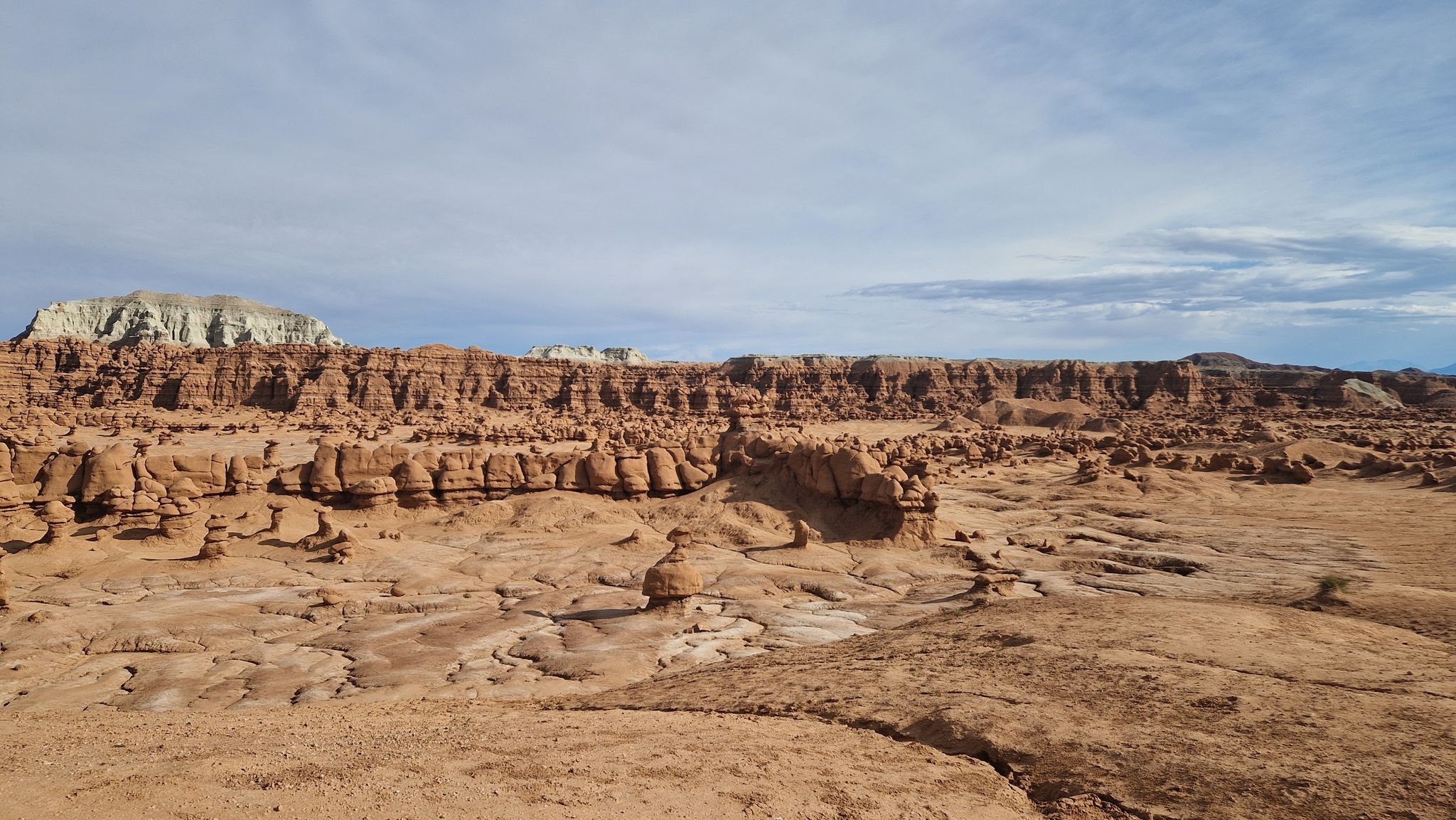 Expansive desert landscape with layered rock formations under a partly cloudy sky. - Carmel Canyon Loop Trail