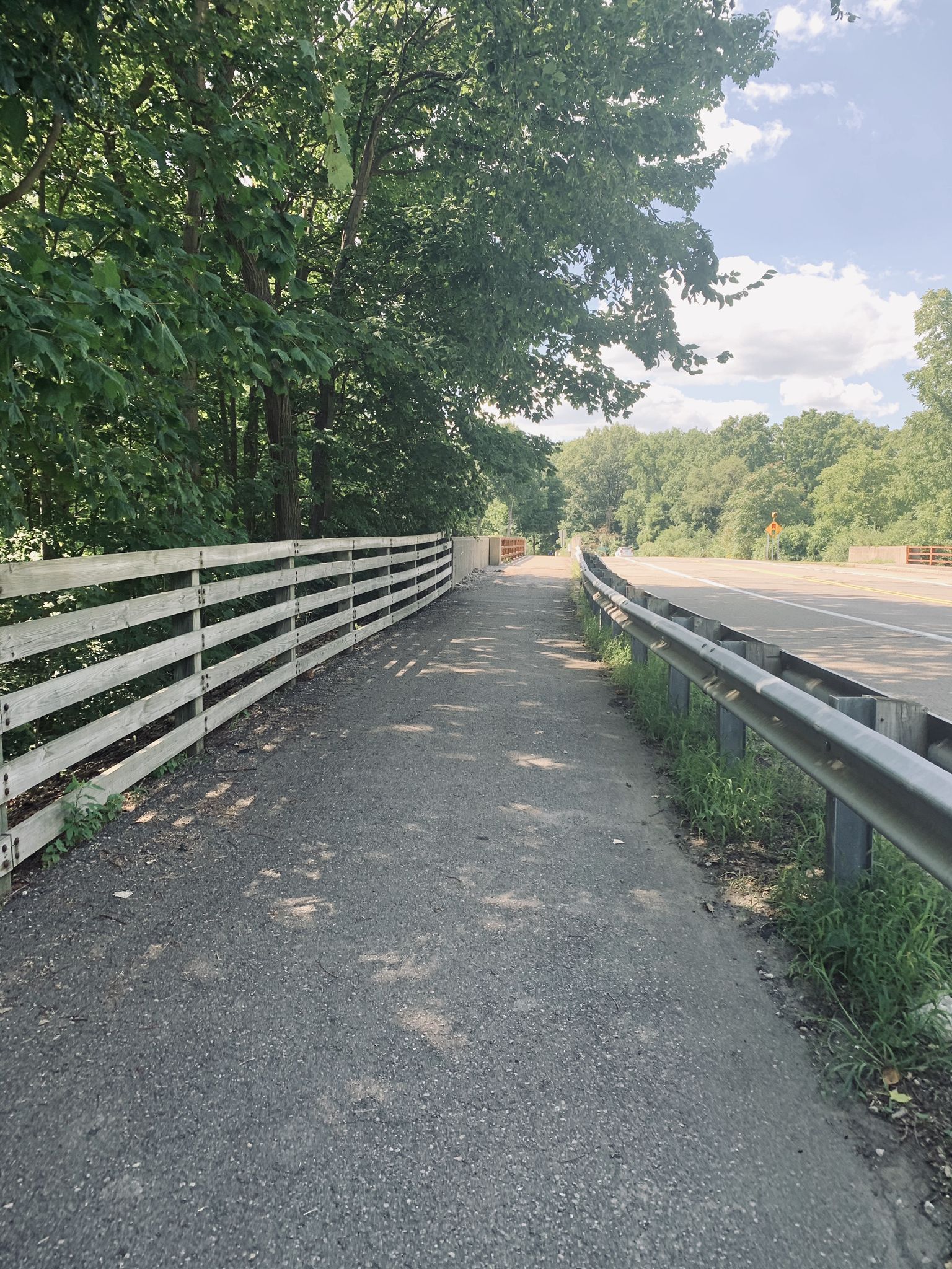 A paved path runs alongside a white fence and road. - Newburgh Lake – Wilcox Lake loop from Plymouth