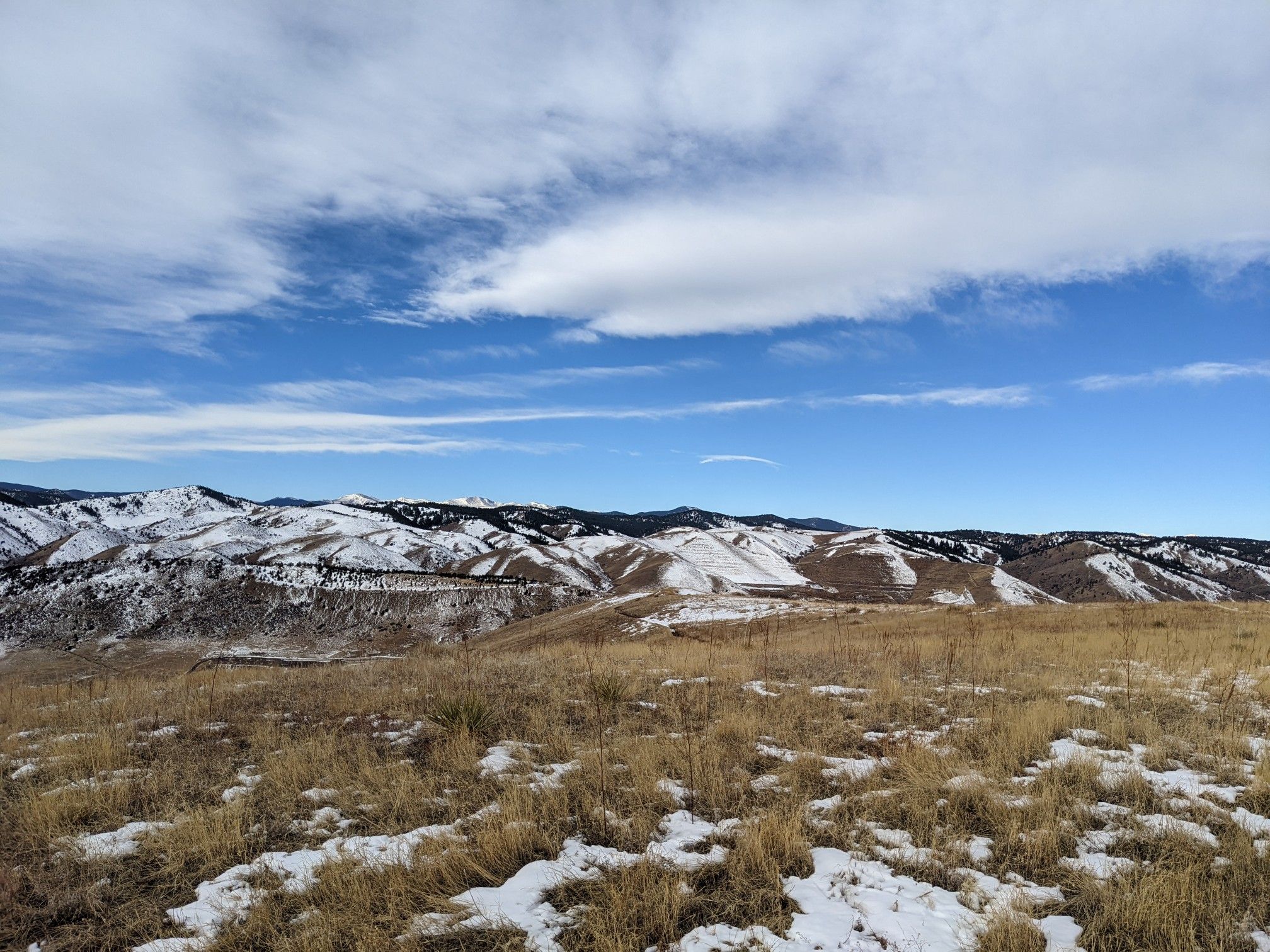 Snowy hills and dry grass under a bright blue sky with white clouds. - Green Mountain Summit Loop