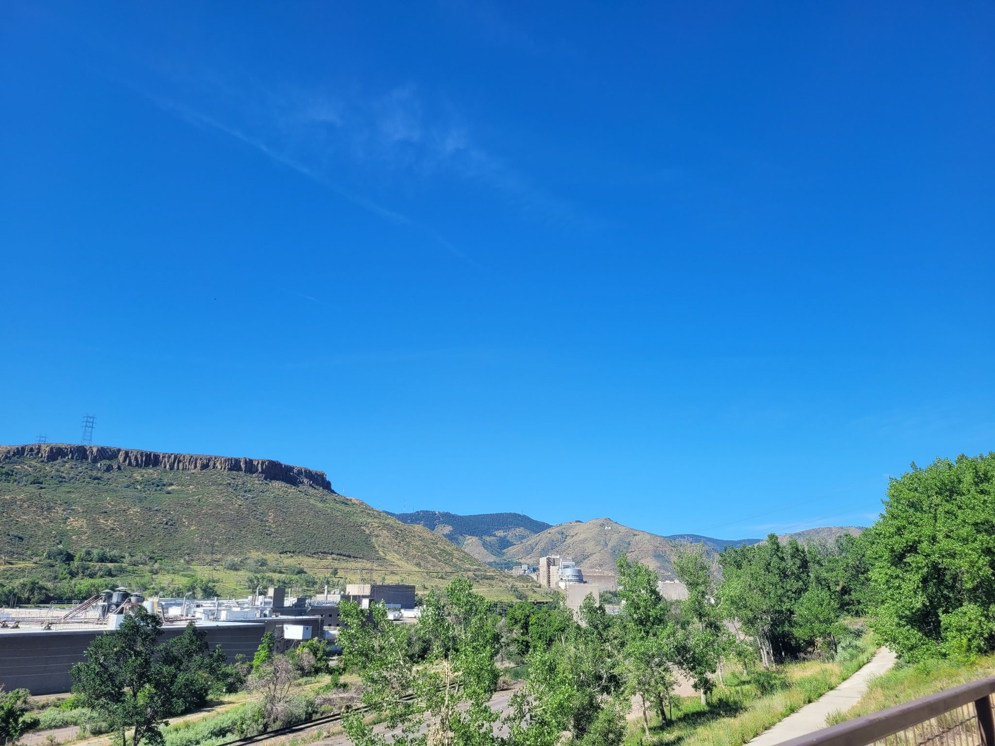 Expansive view of green mountains and distant buildings under a clear blue sky. - Clear Creek Trail Bridge – Clear Creek Trail loop from Lamar