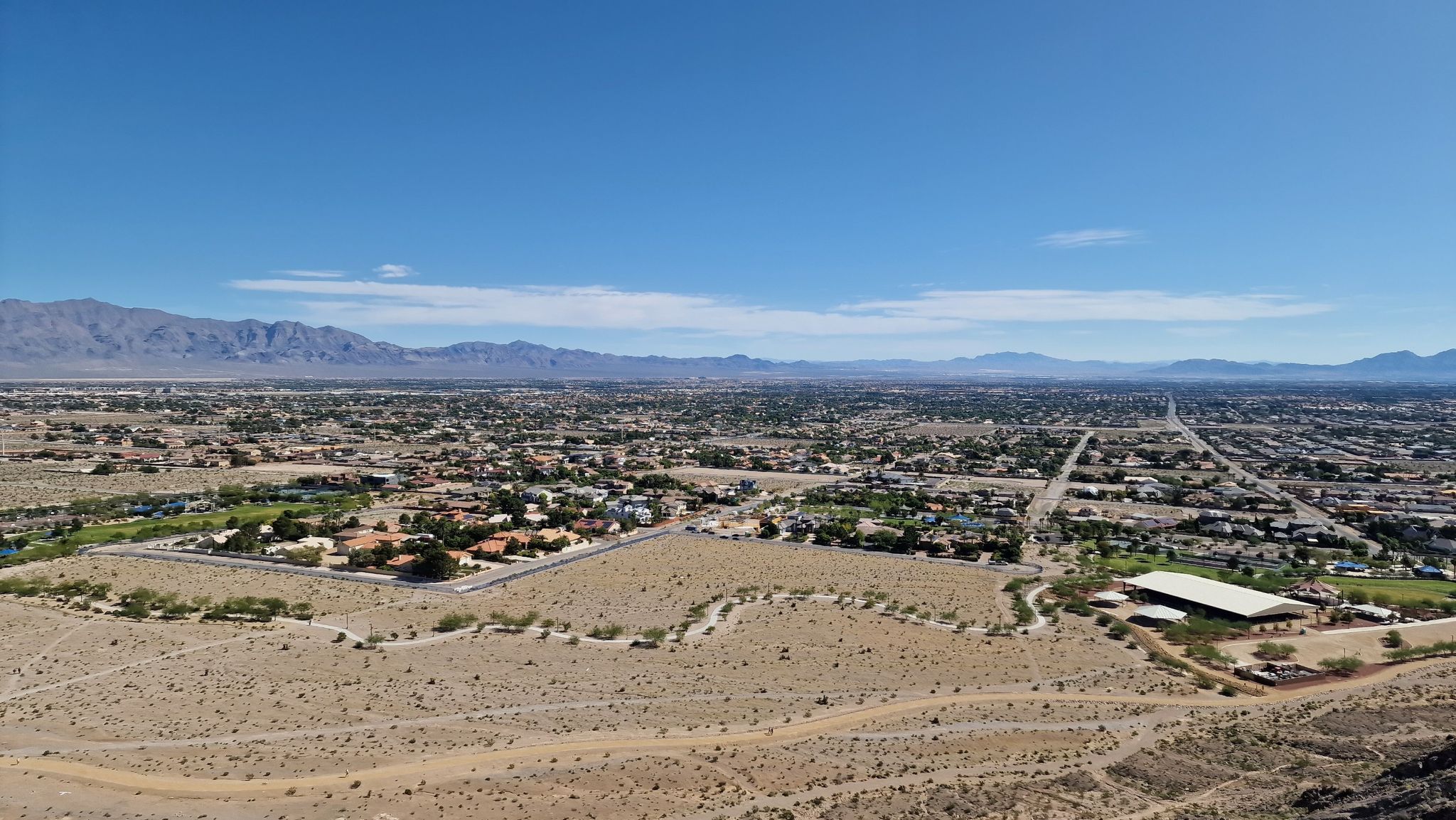 Aerial view of a sprawling desert town with distant mountains under a clear sky. - Lone Mountain Loop
