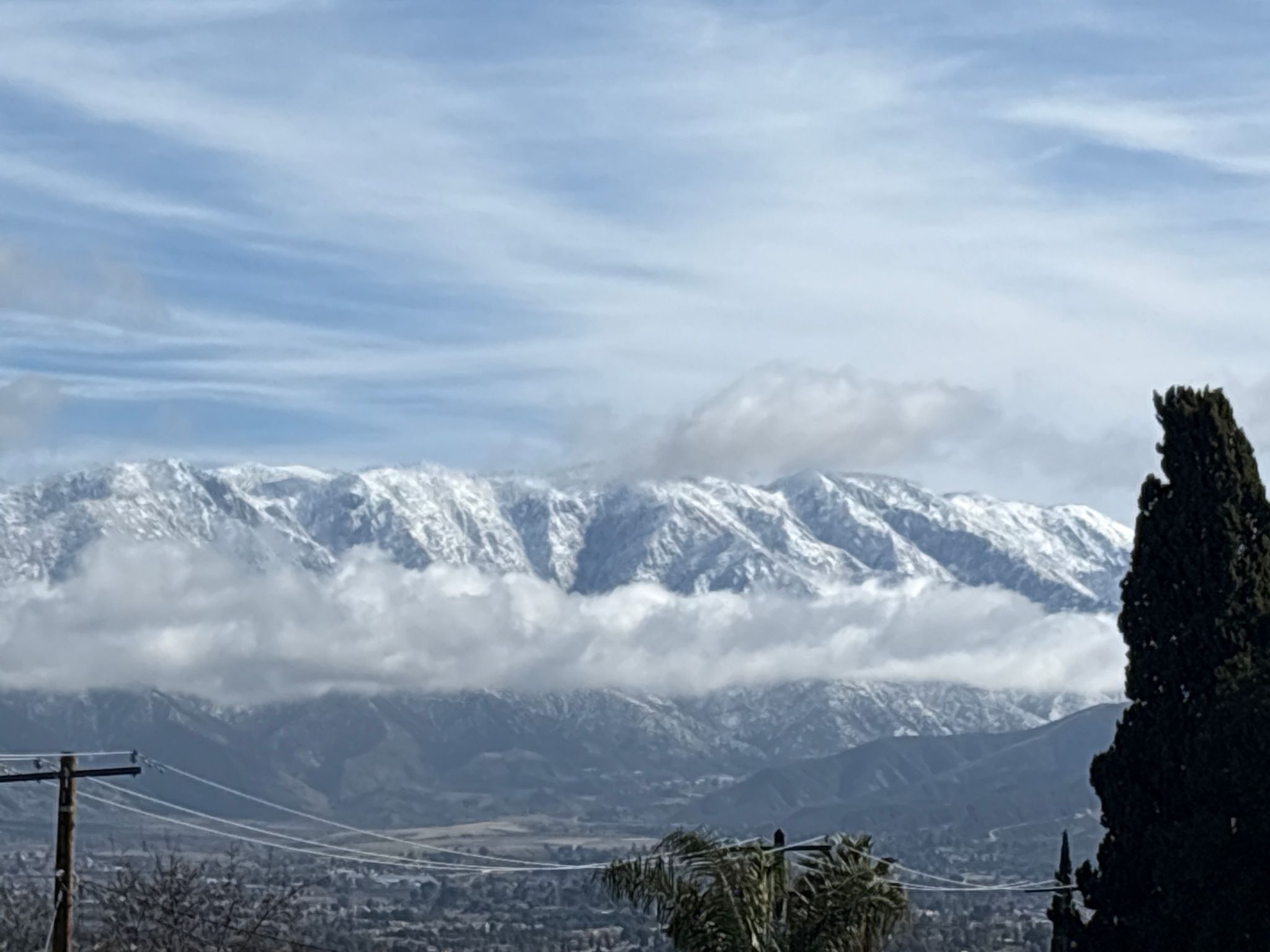 Snow-capped mountains partially obscured by clouds, overlooking a valley. - Oak Glen loop