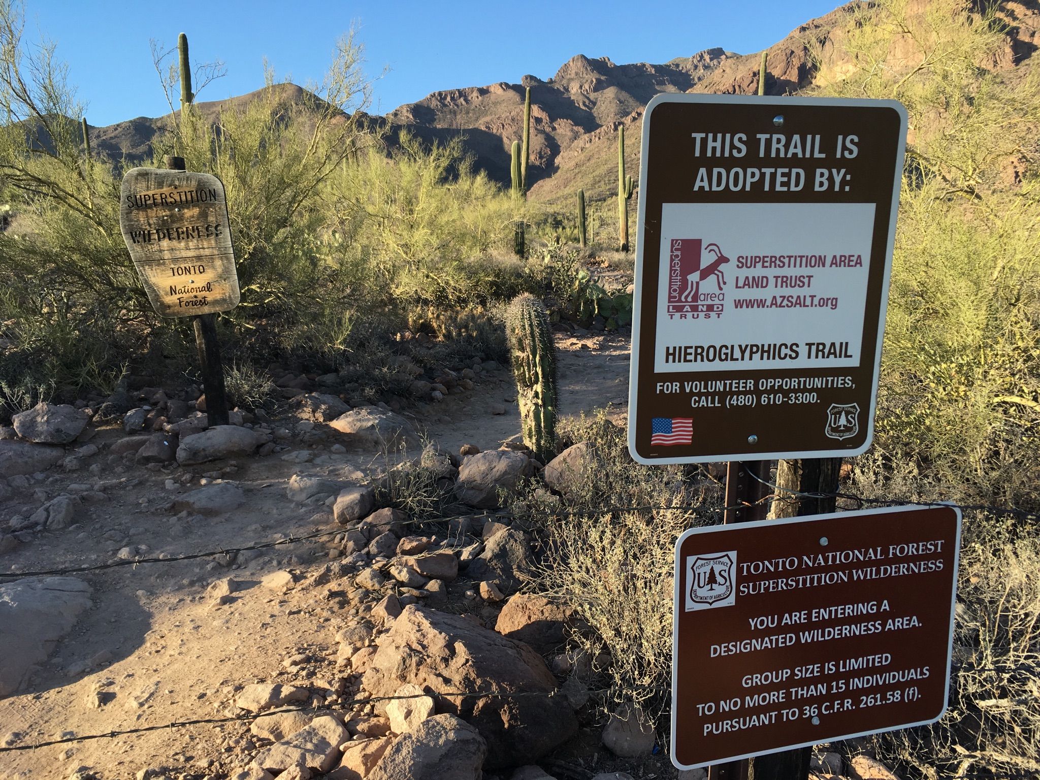 Trail signs in a desert landscape with mountains and cacti under bright sun. - Hieroglyphic Trail #101