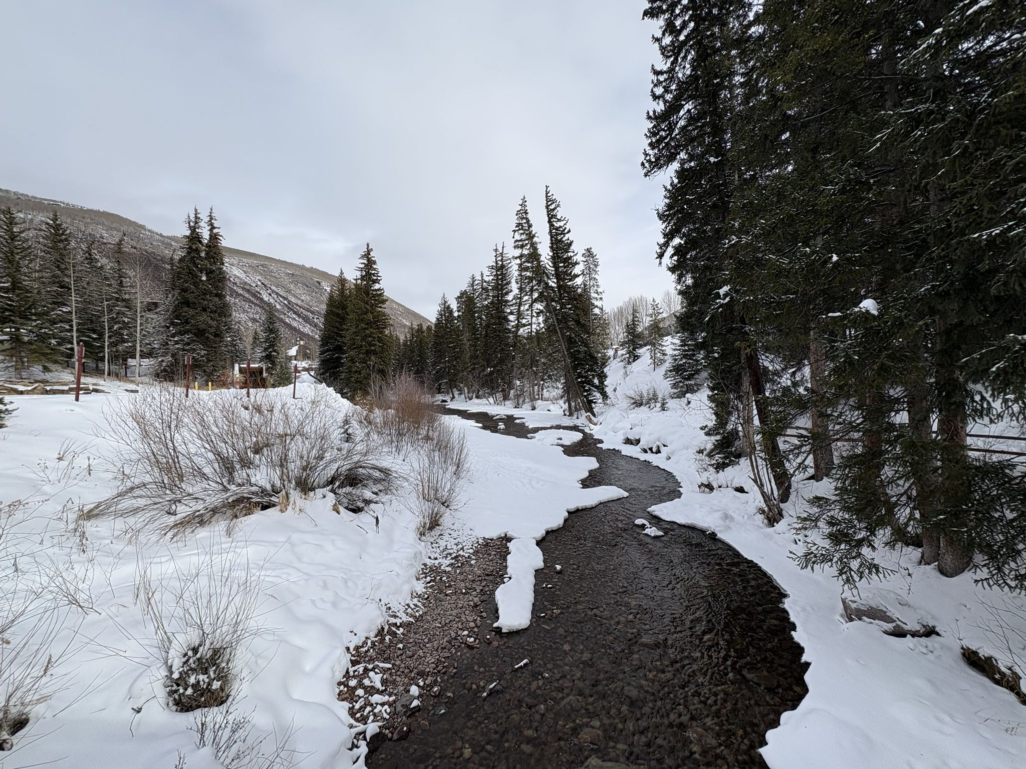 Winding river through a snowy forest under an overcast sky. - Gore Valley Trail