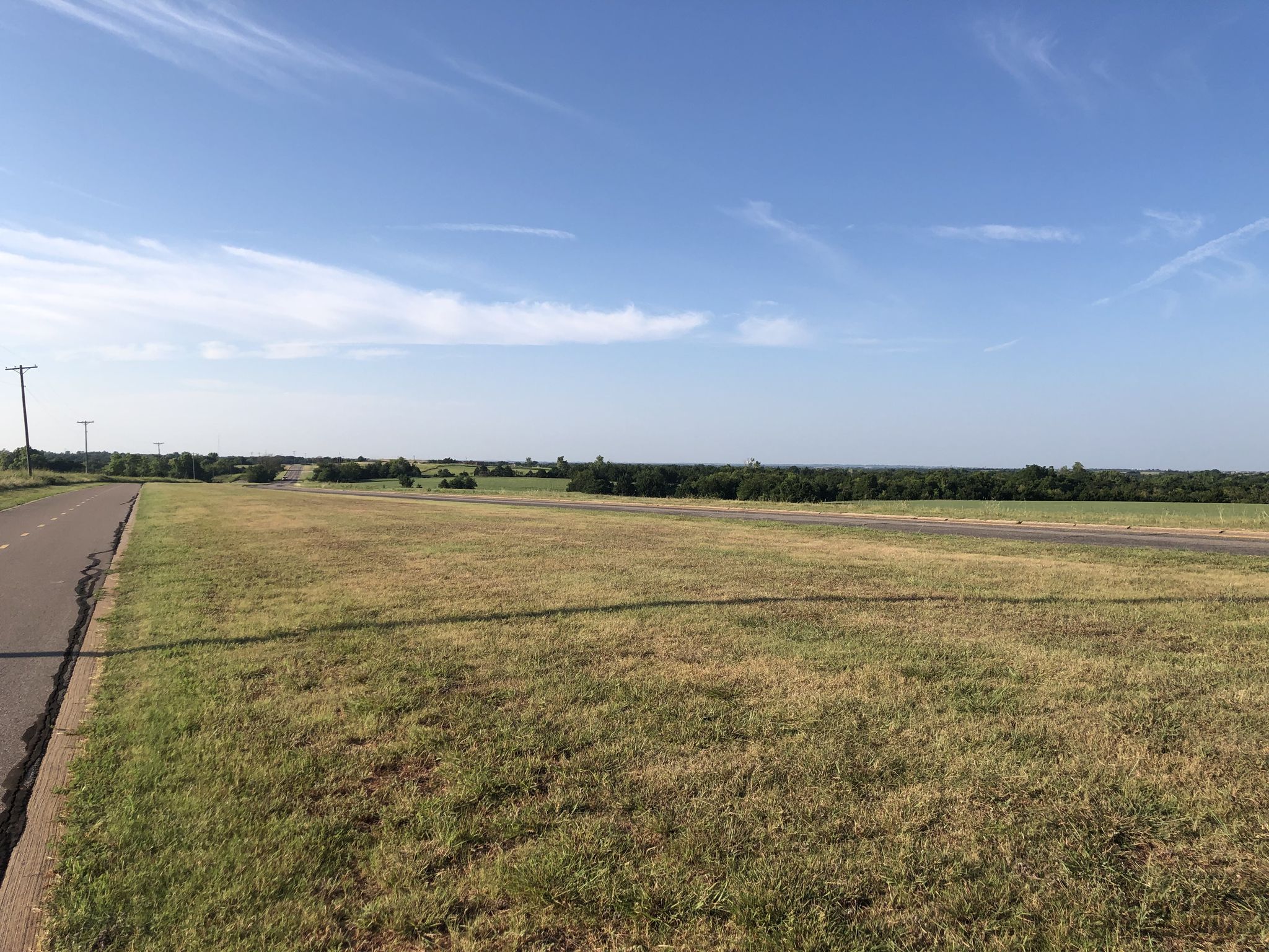 Expansive green field next to a road under a clear blue sky. - Lake Draper Trail