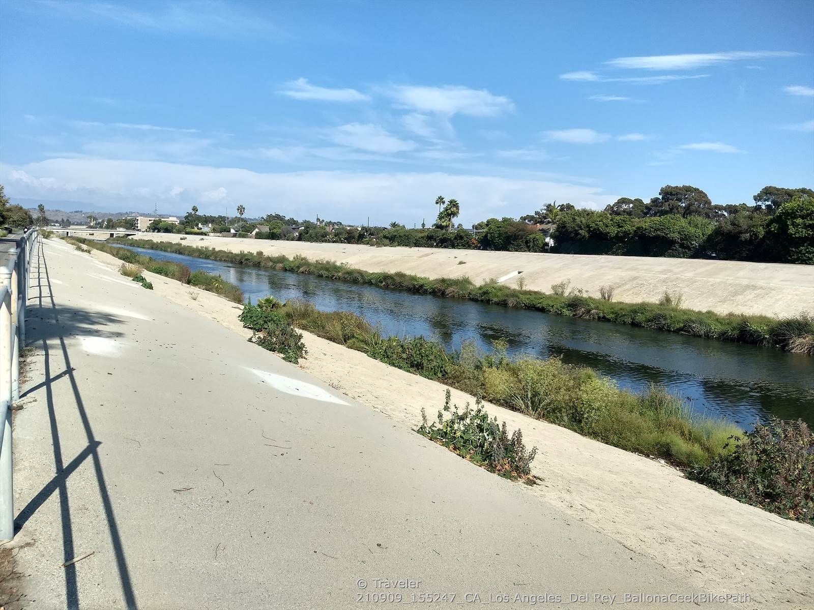 A wide concrete canal with water, a path, and distant buildings on a sunny day. - Marvin Braude and Ballona Creek Bike Path Loop