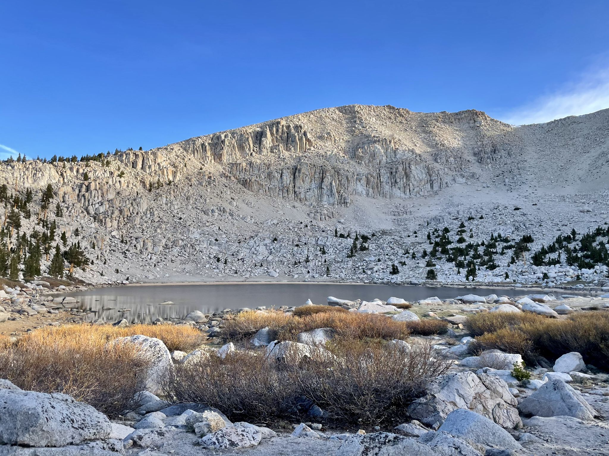 Rocky mountain lake with sparse vegetation under a clear blue sky. - Chicken Spring Lake via Cottonwood Pass Trail