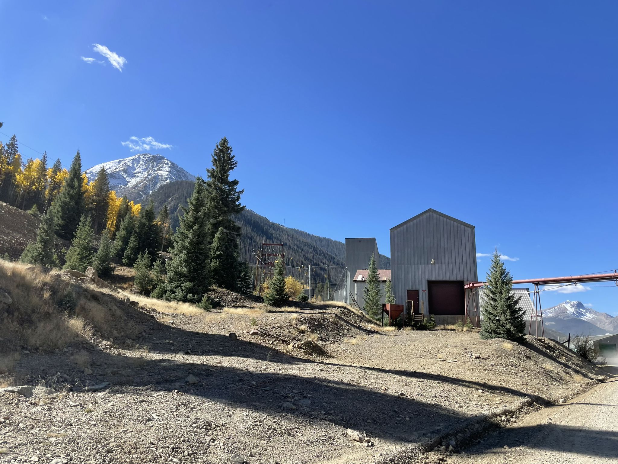 Industrial buildings sit on a hillside with a snowy mountain peak. - Eureka loop