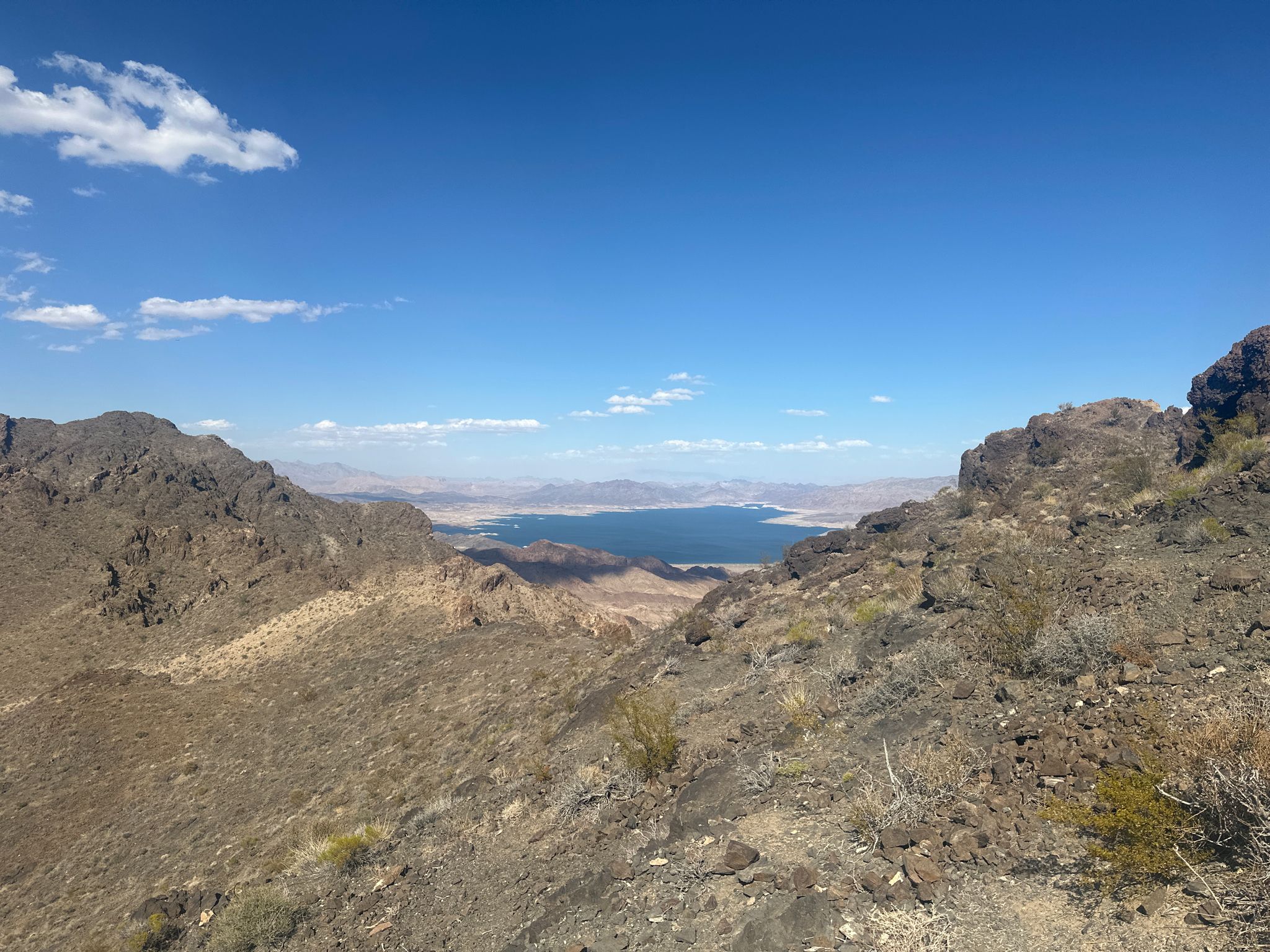 Rocky desert mountains frame a distant lake under a bright blue sky. - Bootleg Canyon and Black Mountain