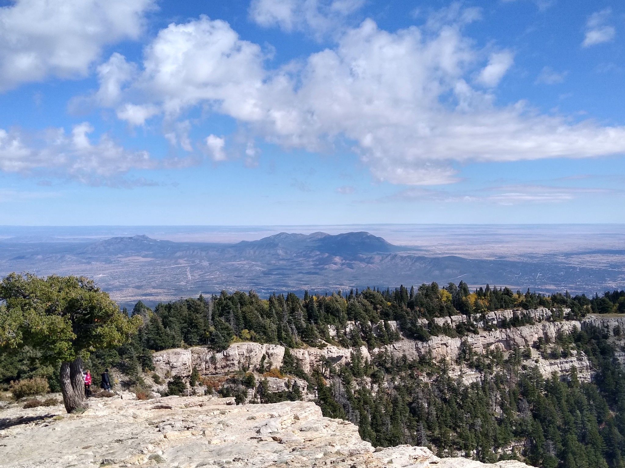 Expansive mountain vista with distant plains under a bright, cloudy sky. - Sandia Peak Aerial Tramway – Kiwanis Cabin loop from Capulin Peak