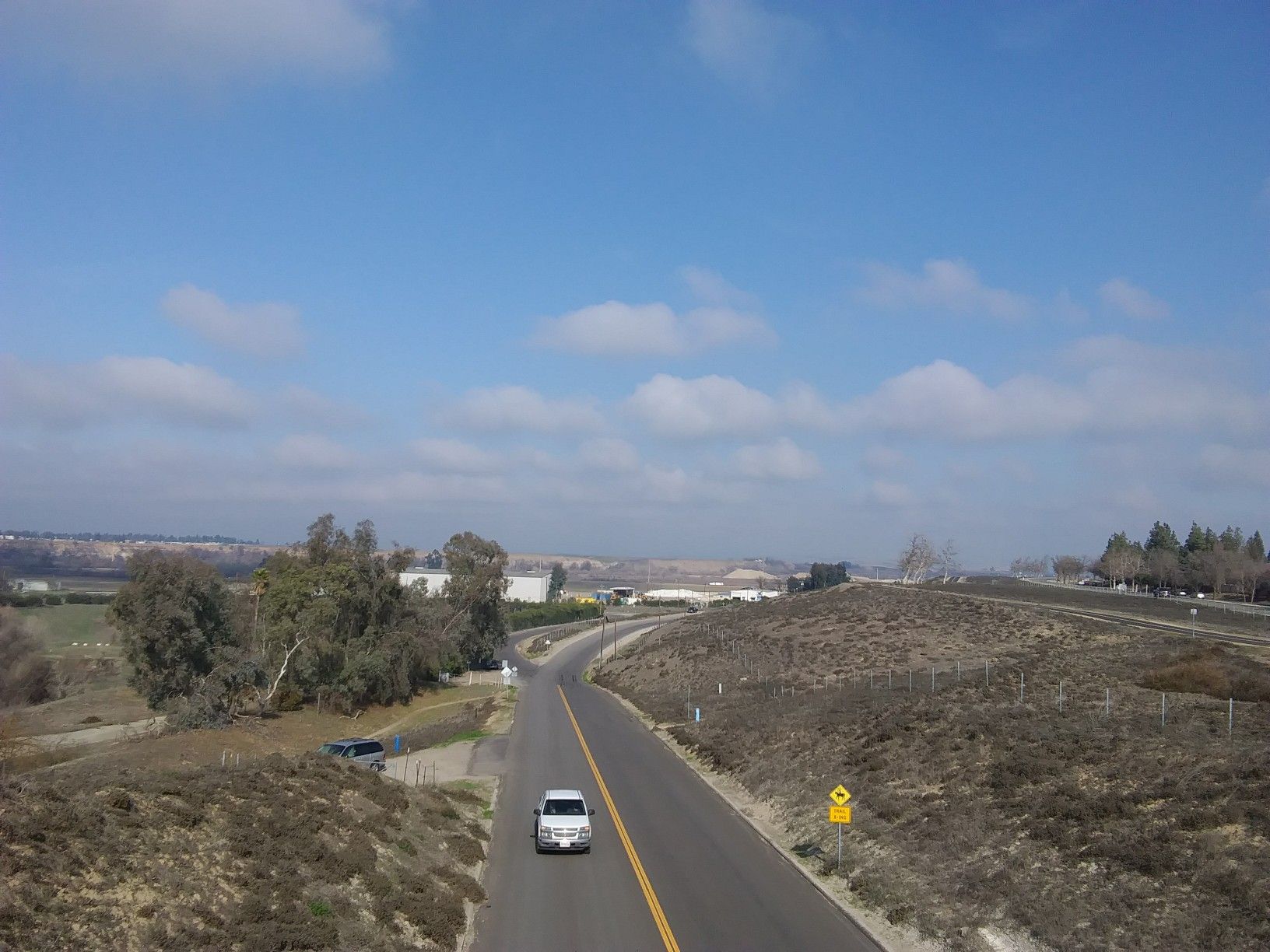 A white van drives on a winding road through dry, rolling hills. - Lewis S. Eaton Bike Trail Loop