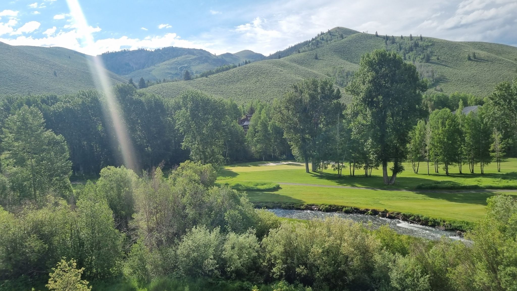 Sunny valley with a river, green field, and forested mountains under a bright sky. - Proctor Mountain Loop