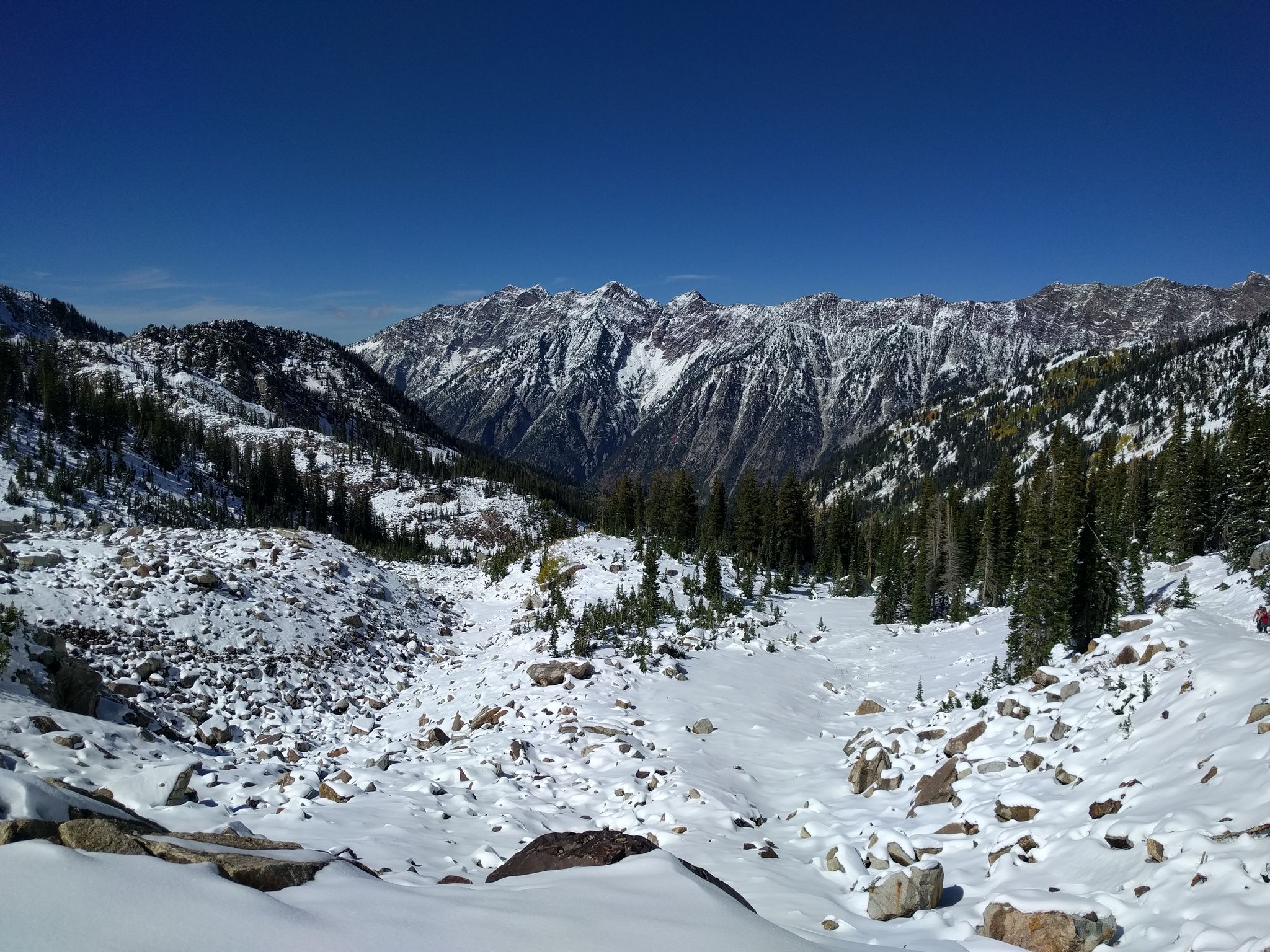 A vast snow-covered mountain valley with rugged peaks under clear blue sky. - White Pine Trail