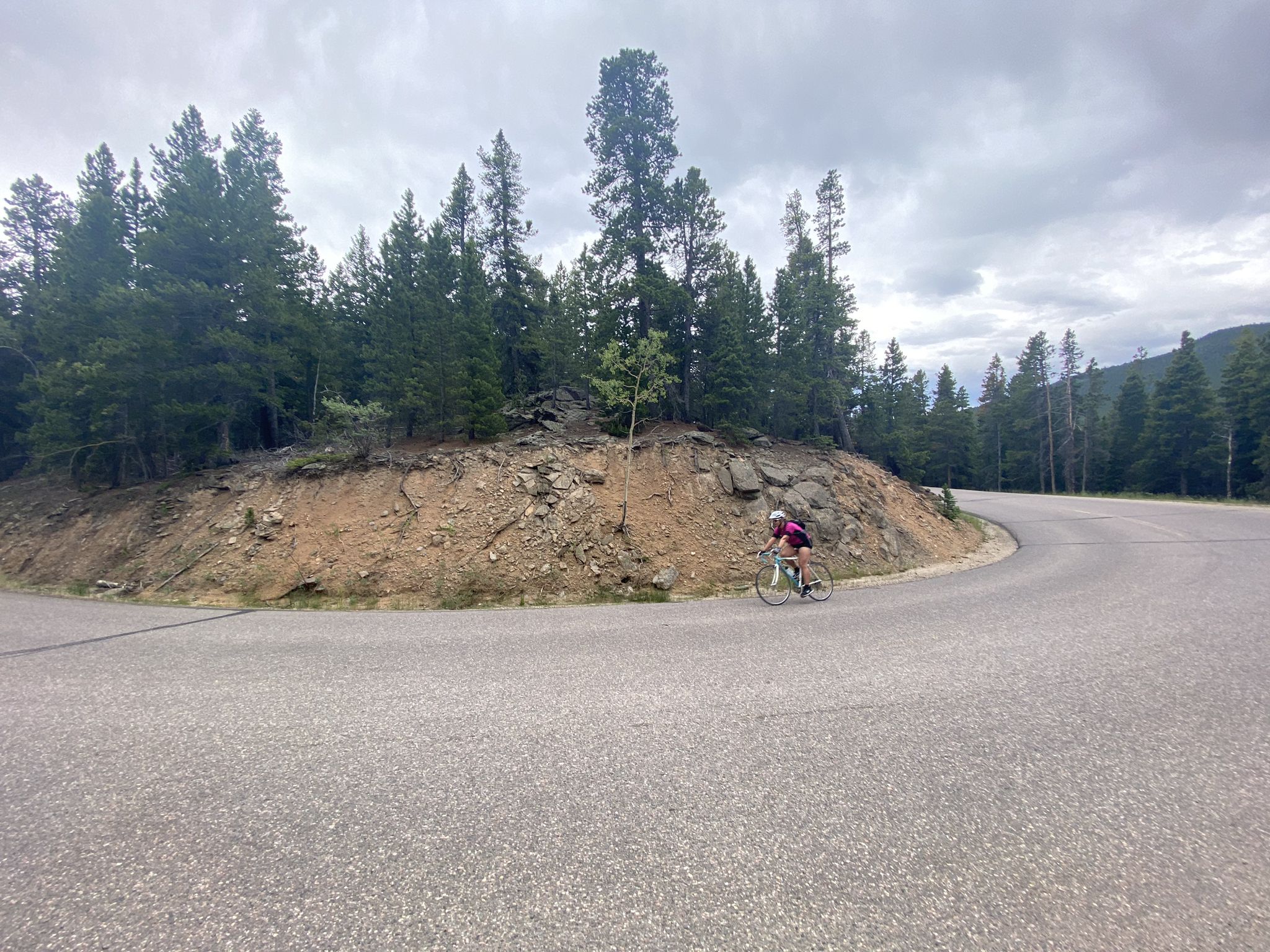 Cyclist on a winding mountain road under an overcast sky. - Witter Gulch Road – Mestaa'Ėhehe Pass Summit loop from Hidden Valley