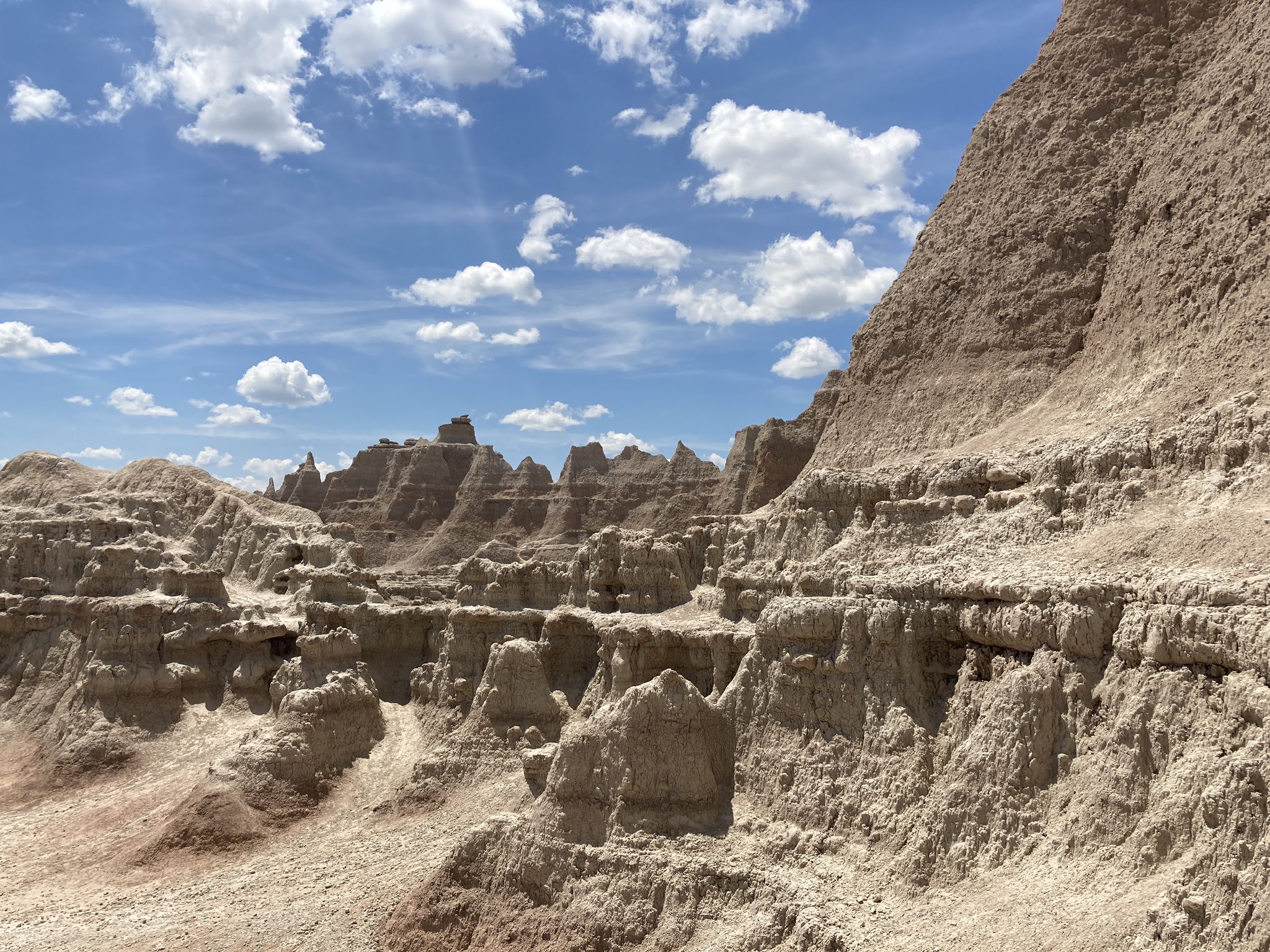 Jagged, eroded rock formations and spires under a bright blue sky with clouds. - Door Trail