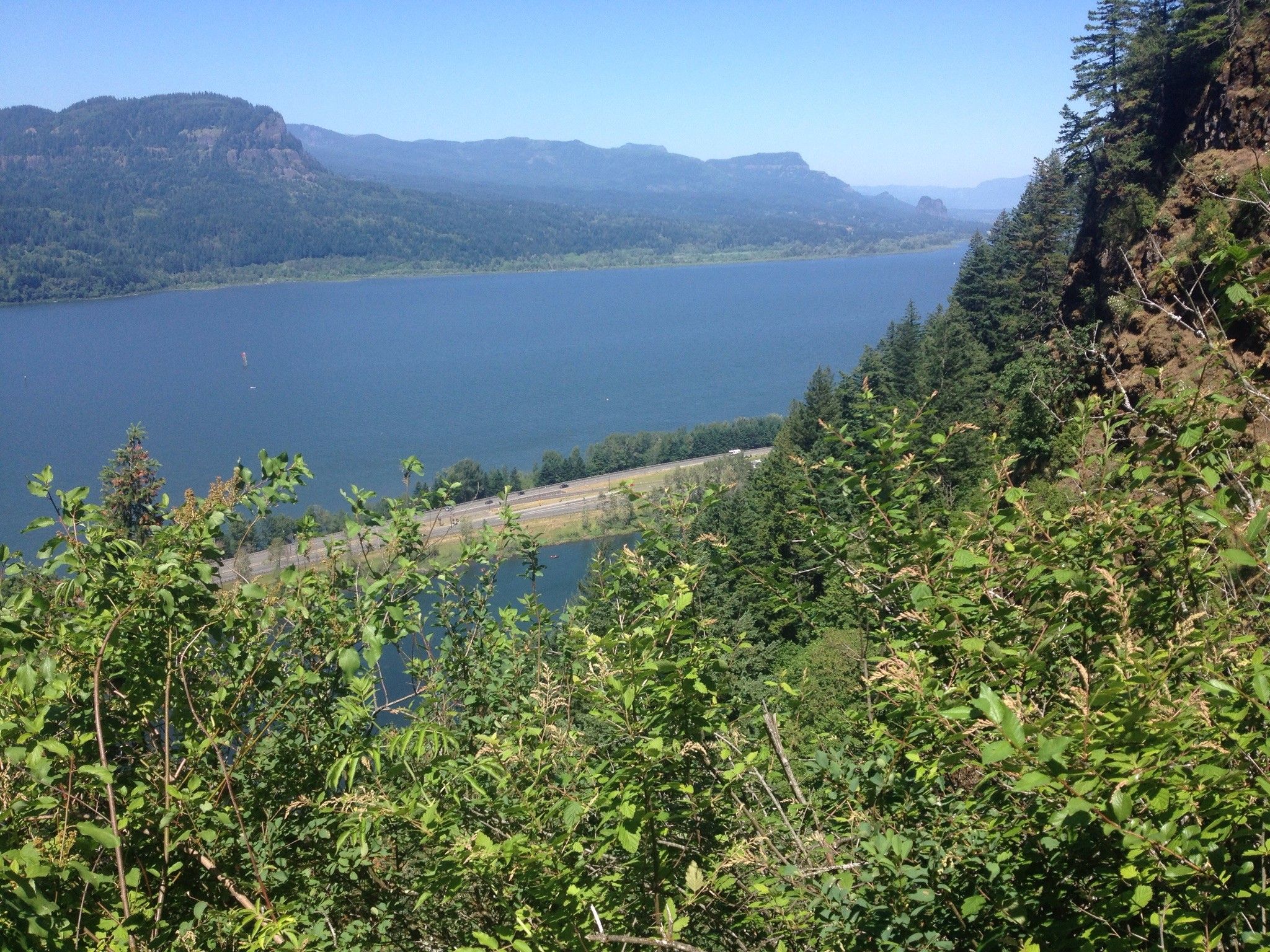A wide river with a highway on its bank, surrounded by green mountains. - Fairy Falls – Wahkeena Falls loop from Benson State Recreation Area