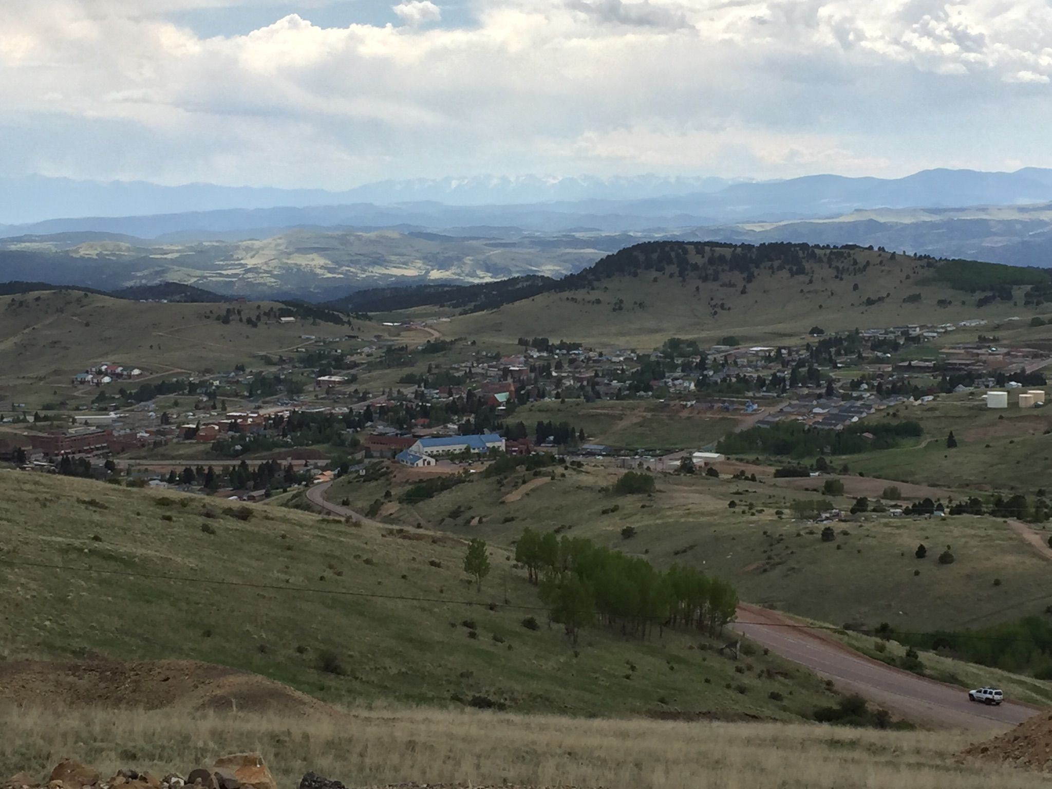 A town in a wide valley surrounded by green hills under an overcast sky. - Mueller State Park from Cripple Creek
