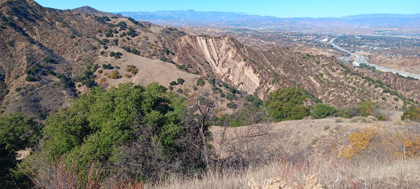 Panoramic view of rugged, arid mountains and a distant valley with a river. - East and Rice Canyon Loop