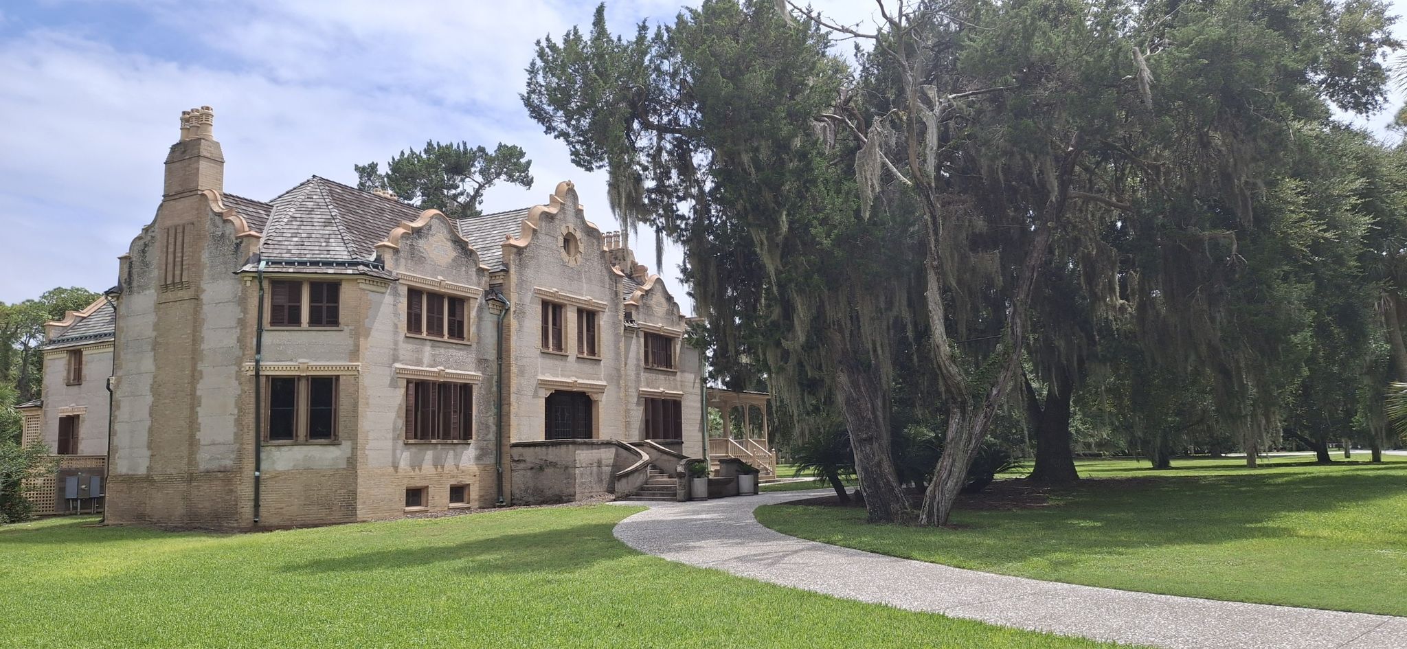 A large historic building with a winding path on a green lawn with mossy trees. - Driftwood Beach – The Horton House loop from Fishing Center Parking