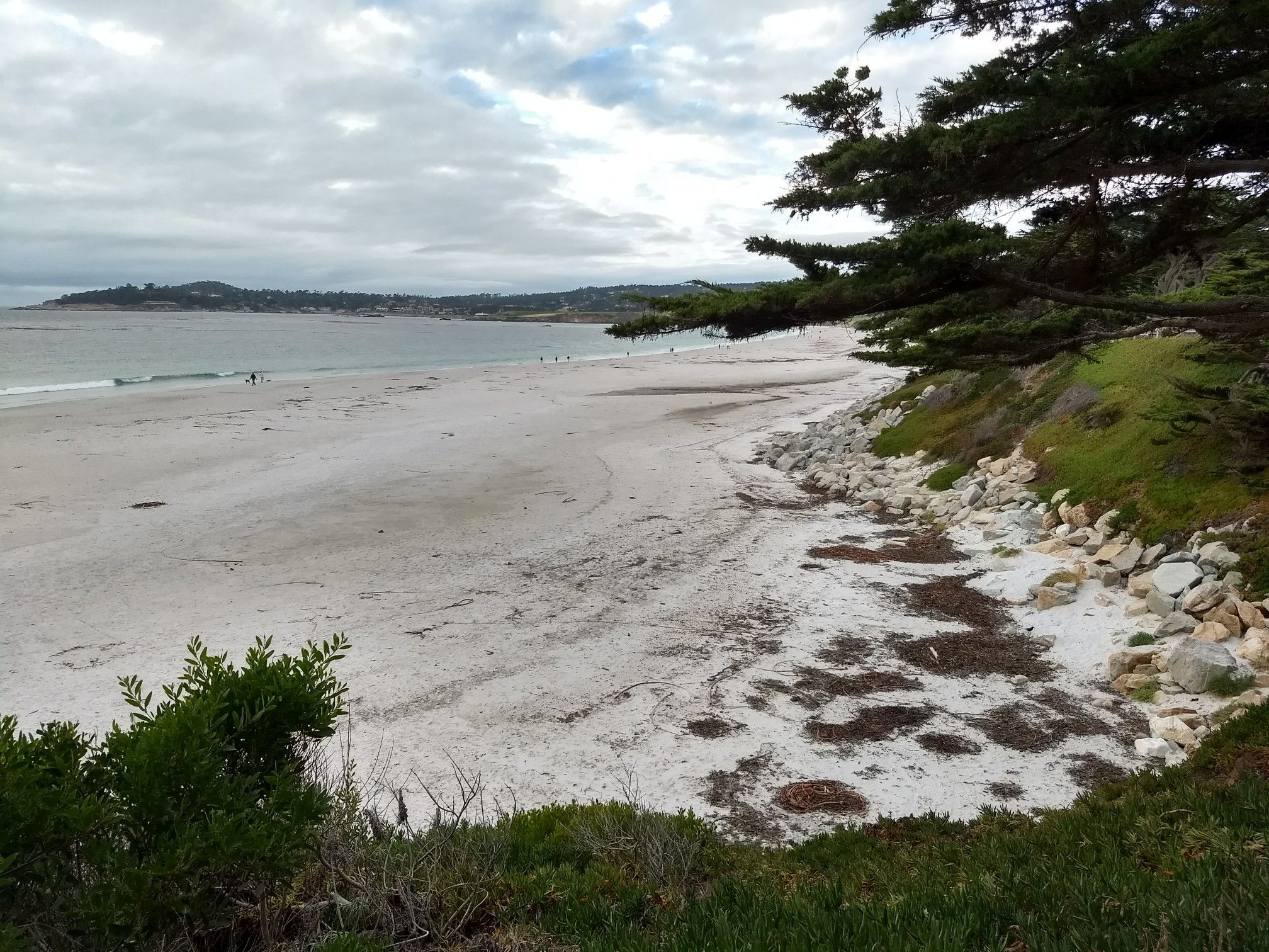 Overcast view of a wide sandy beach with rocky shore and distant ocean. - China Rock – Point Joe loop from Carmel-by-the-Sea
