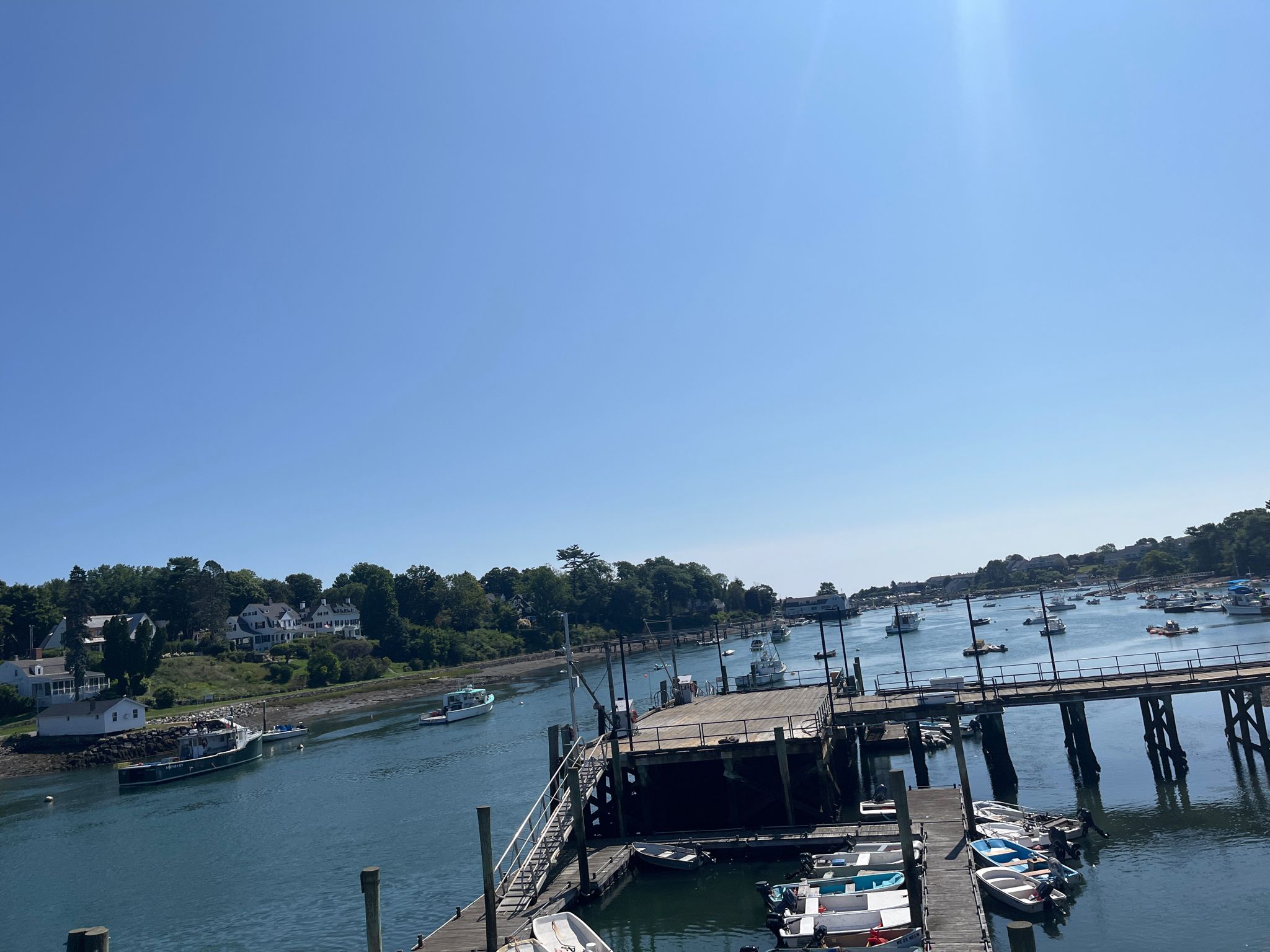 Boats docked at a wooden pier in a sunny, calm bay. - Long Sands Beach – Long Sands Beach loop from Scituate Pond Dam