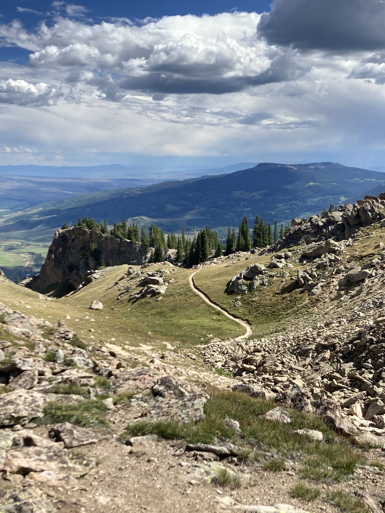 Winding dirt trail through a rocky mountain pass under a partly cloudy sky. - Upper Westside to Crested Butte