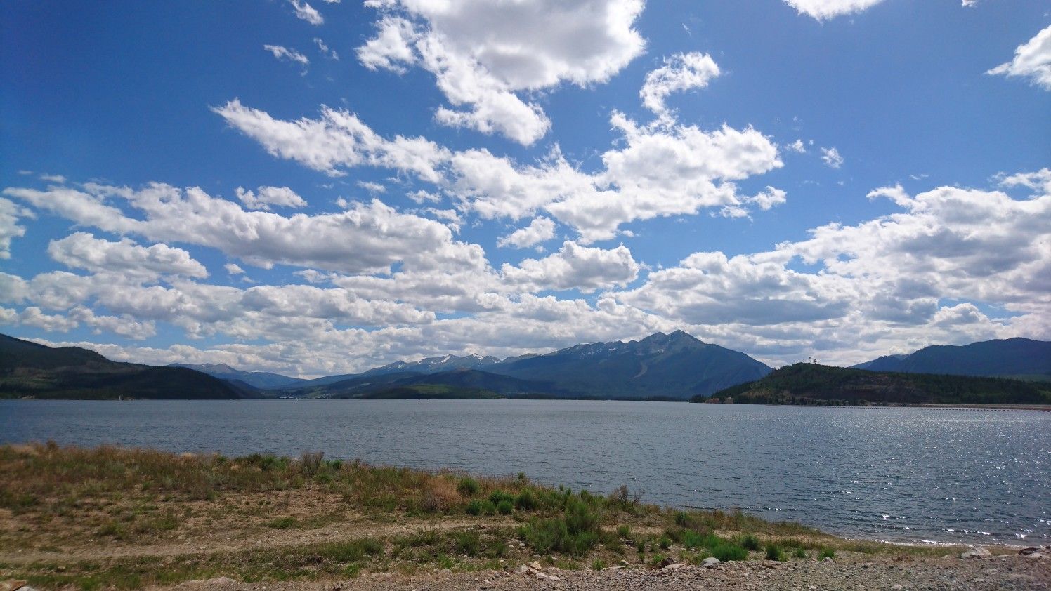 Wide lake with distant mountains under a bright blue, cloudy sky. - Blue River Trail loop from Dillon