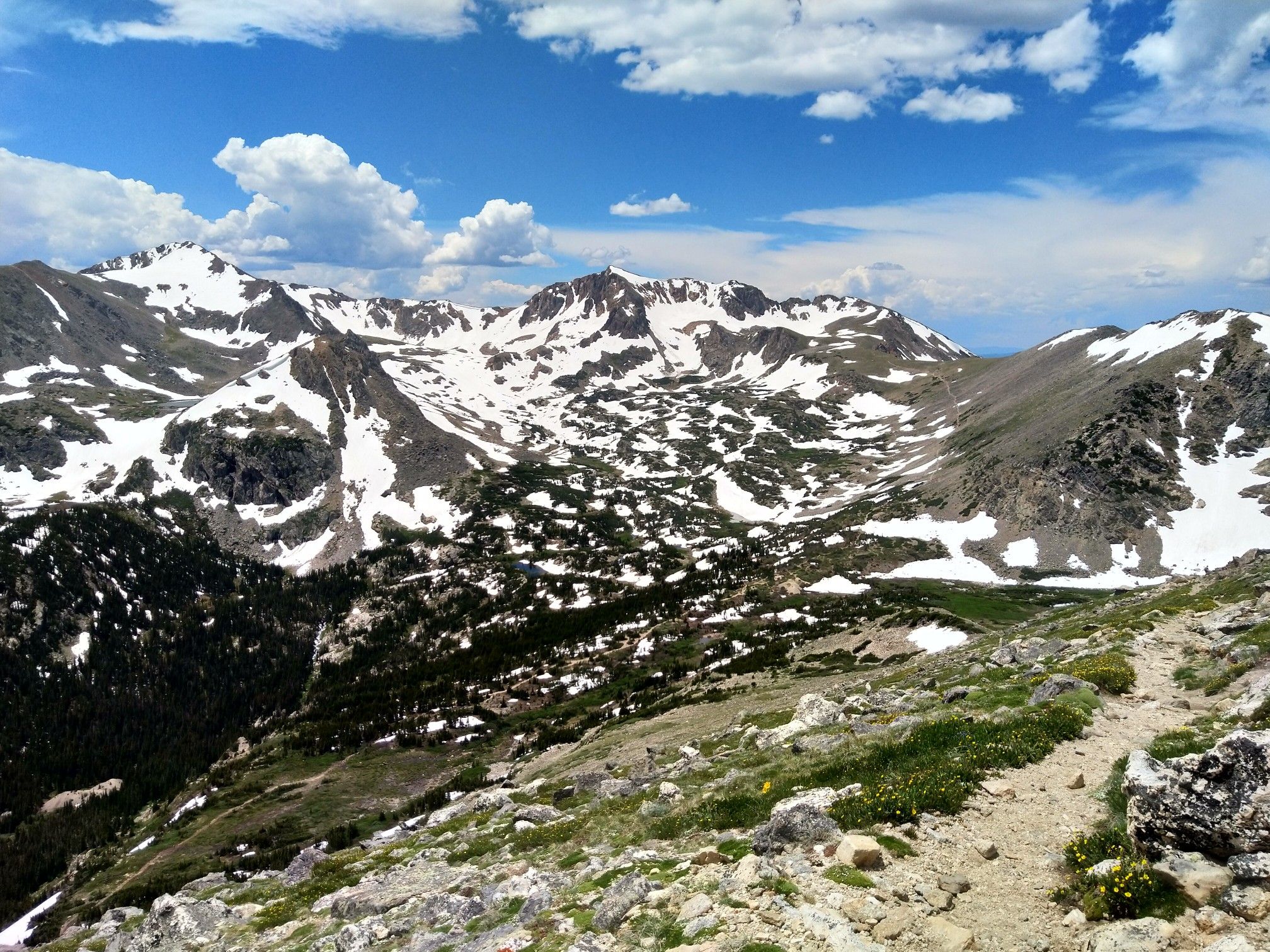 Panoramic view of rugged, snow-dusted mountains and green valleys under a blue sky. - South Arapaho Peak via Arapaho Glacier Trail