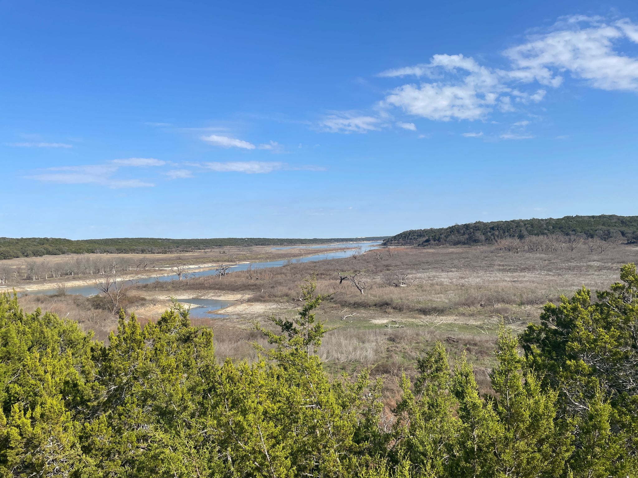 Panoramic view of a wide river valley surrounded by green trees under a blue sky. - Good Water Trail Loop