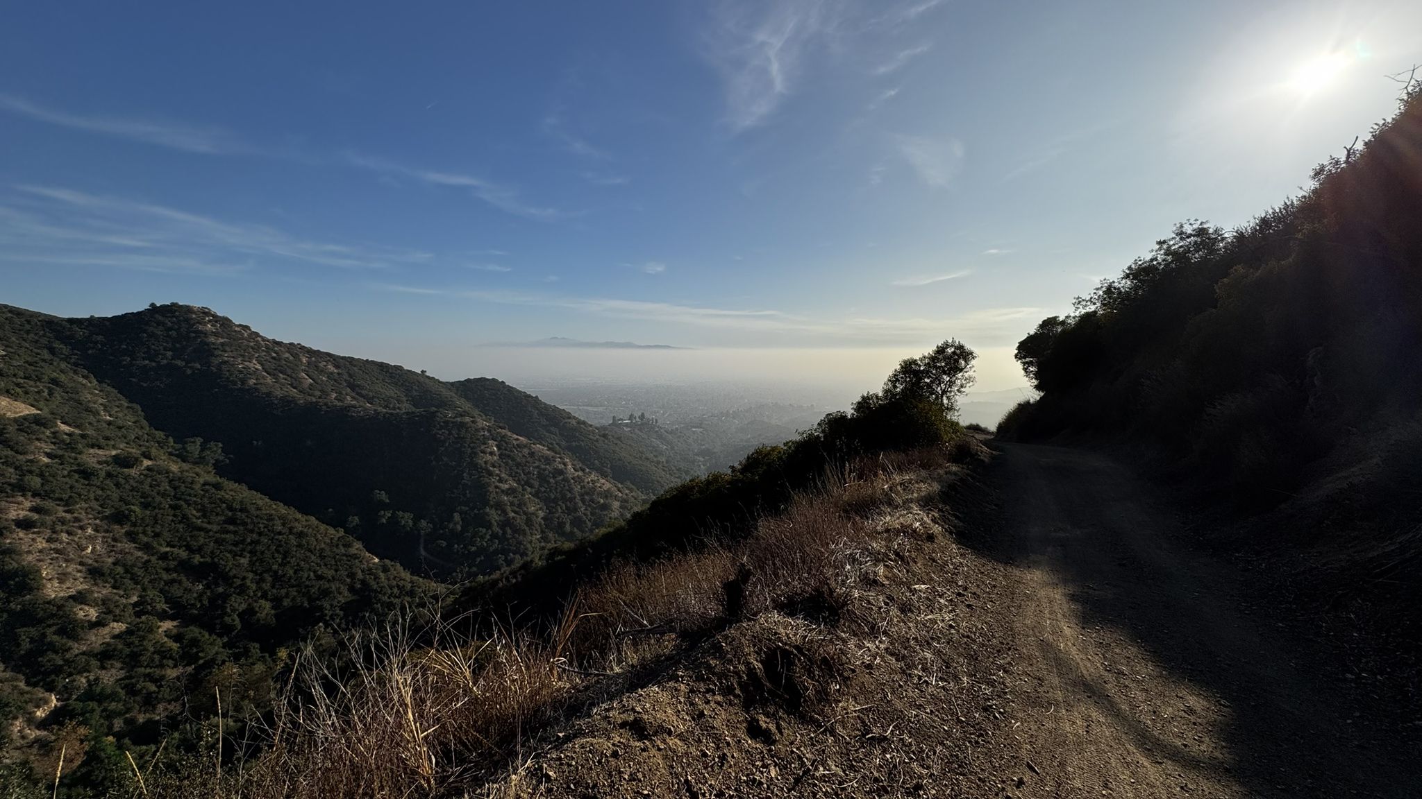 Dirt path on a sunny hillside overlooking hazy mountains and valleys. - Potato Mountain Loop