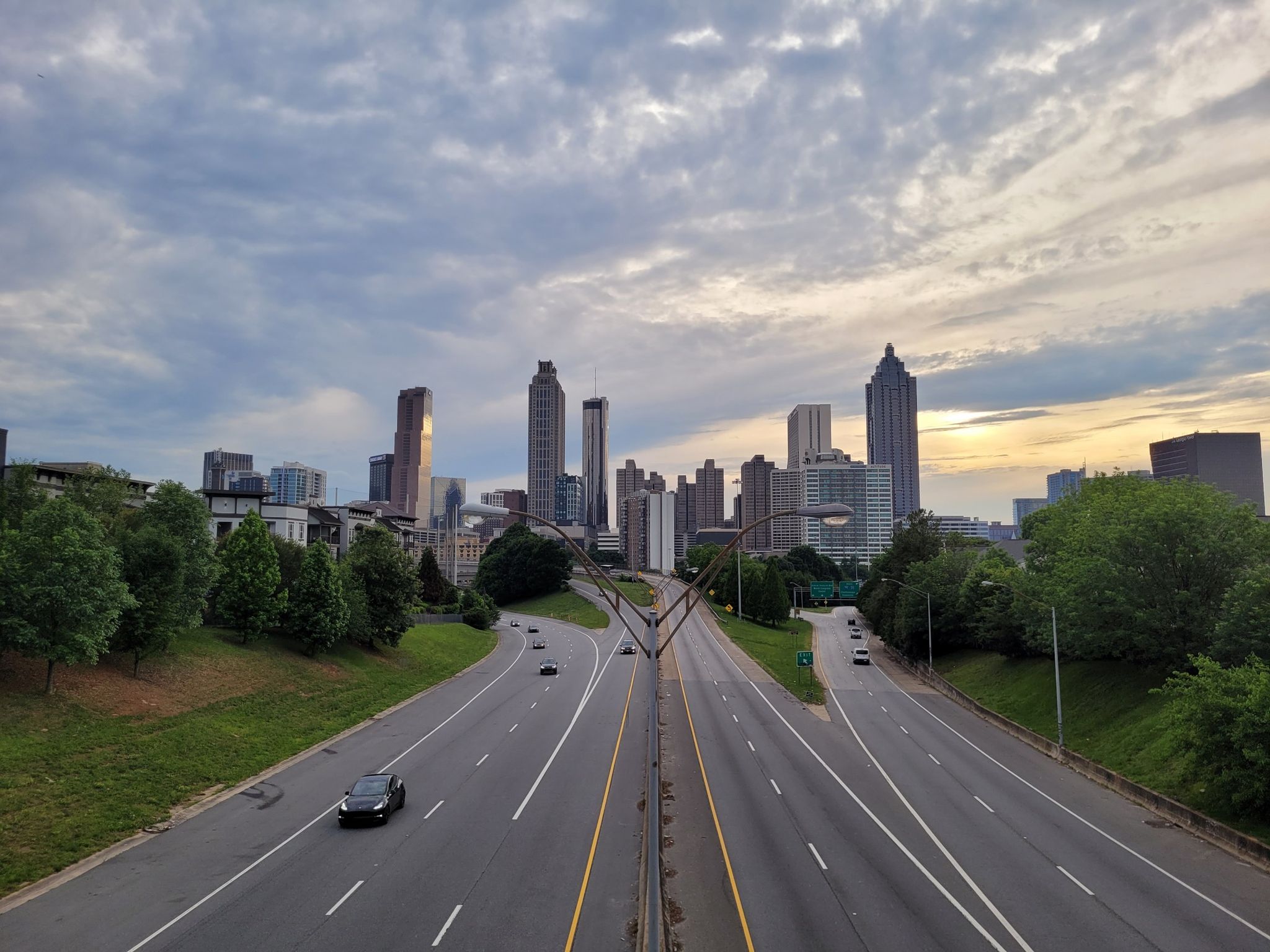 An empty highway leading to a city skyline under a cloudy sunset sky. - Inman Park – Freedom Park Pathway loop from Stone Mountain