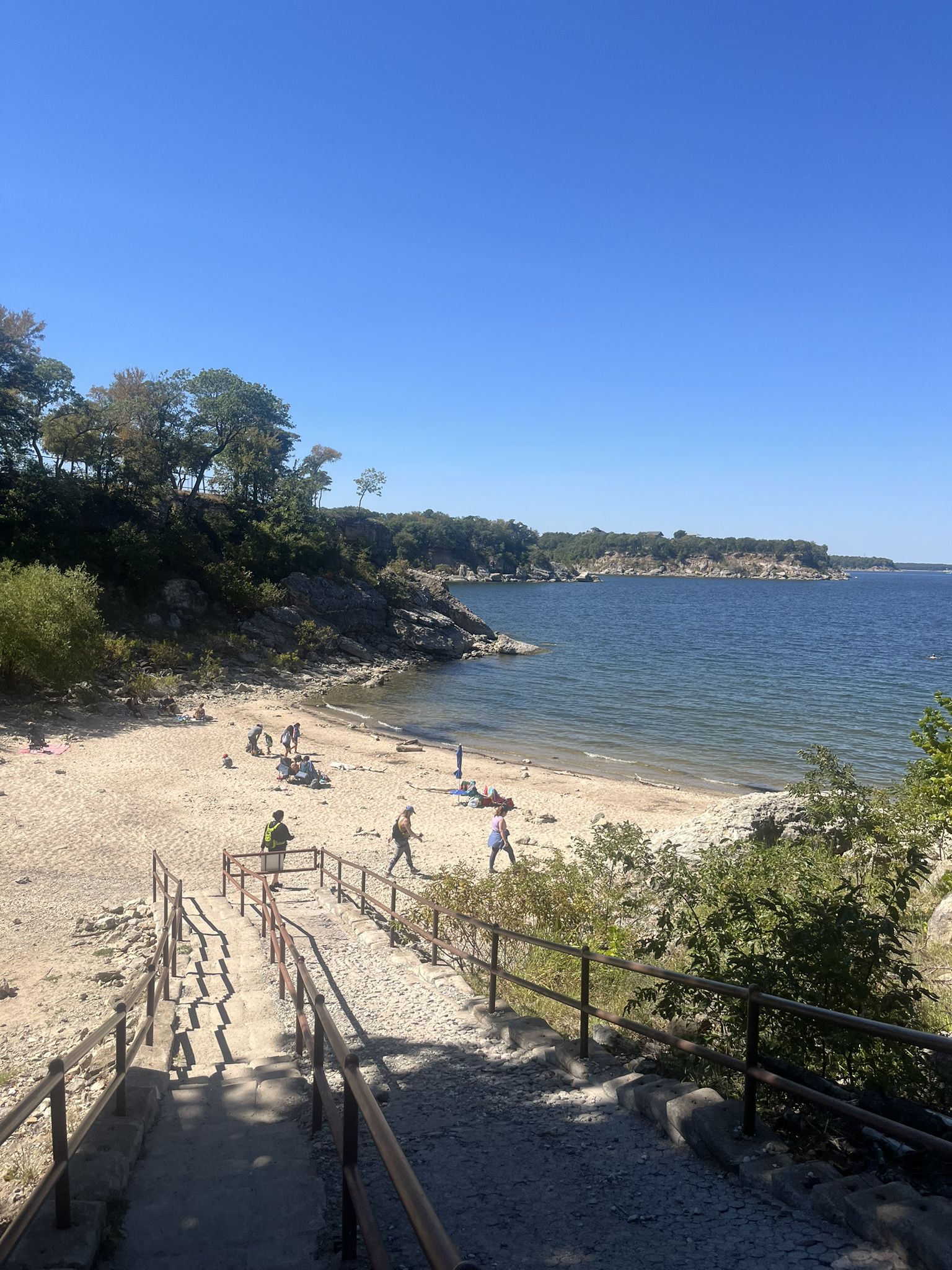Sunny beach with people, calm lake, and stairs leading down to the sand. - Hiking loop from Eisenhower State Park