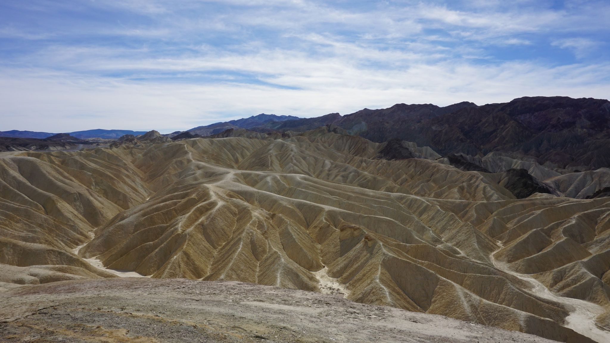 Intricately eroded badlands formations with distant mountains under a partly cloudy sky. - Mount Perry via Dante's Ridge