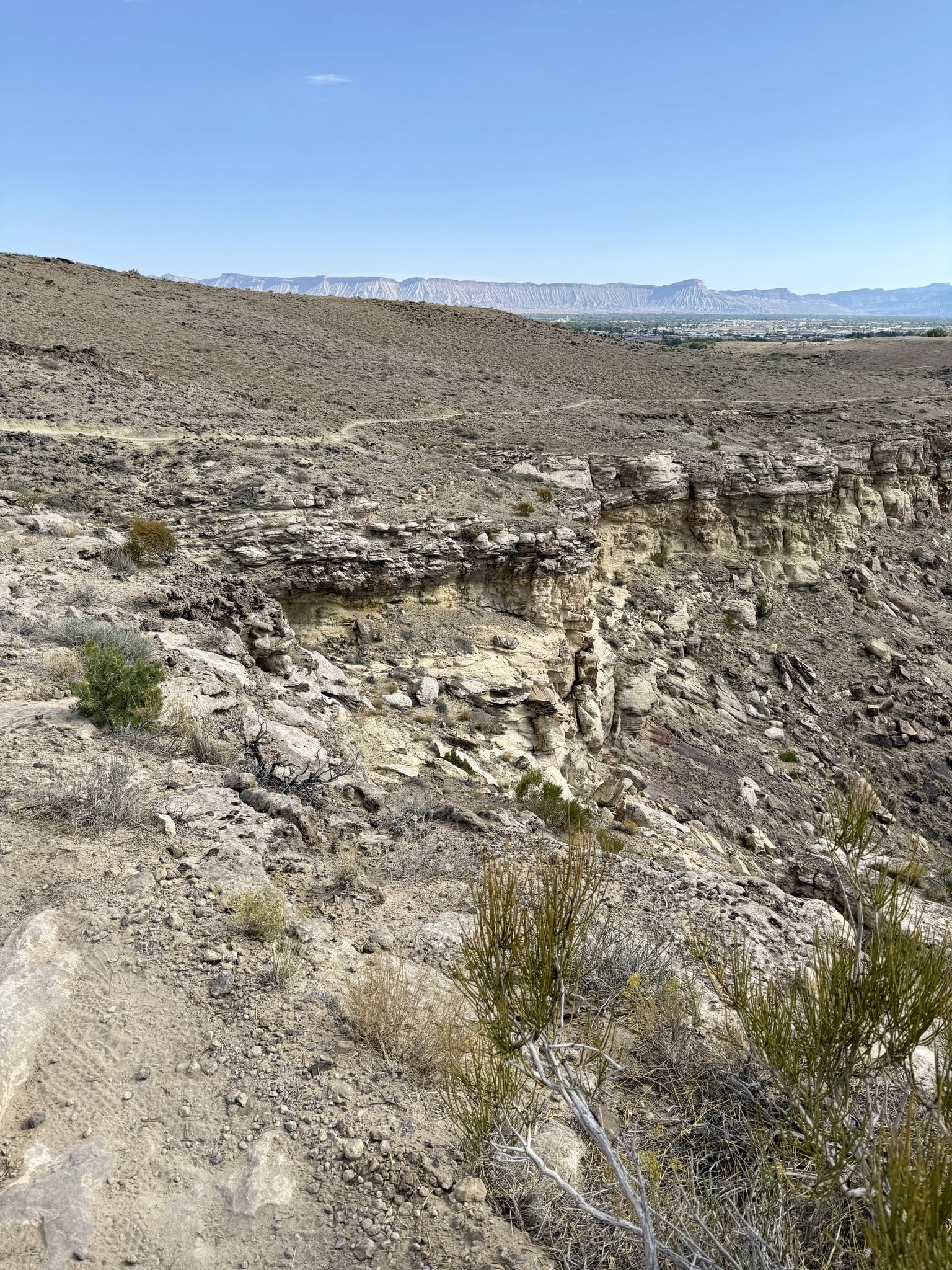 Sunny view of a rocky canyon edge and distant arid mountains. - Miramonte Rim Trail loop from White Cap