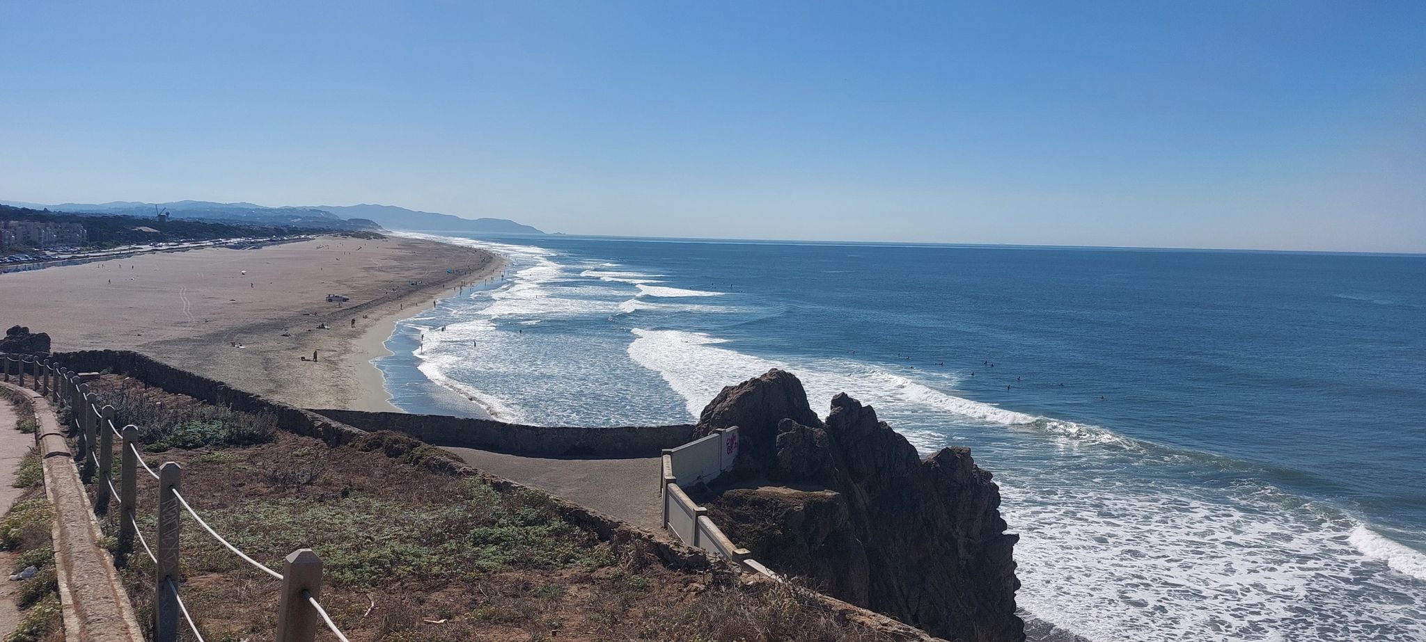 Elevated view of a long sandy beach, ocean waves, and a rocky cliff. - Murphy Windmill – Golden Gate Park loop from Duboce Avenue & Noe Street