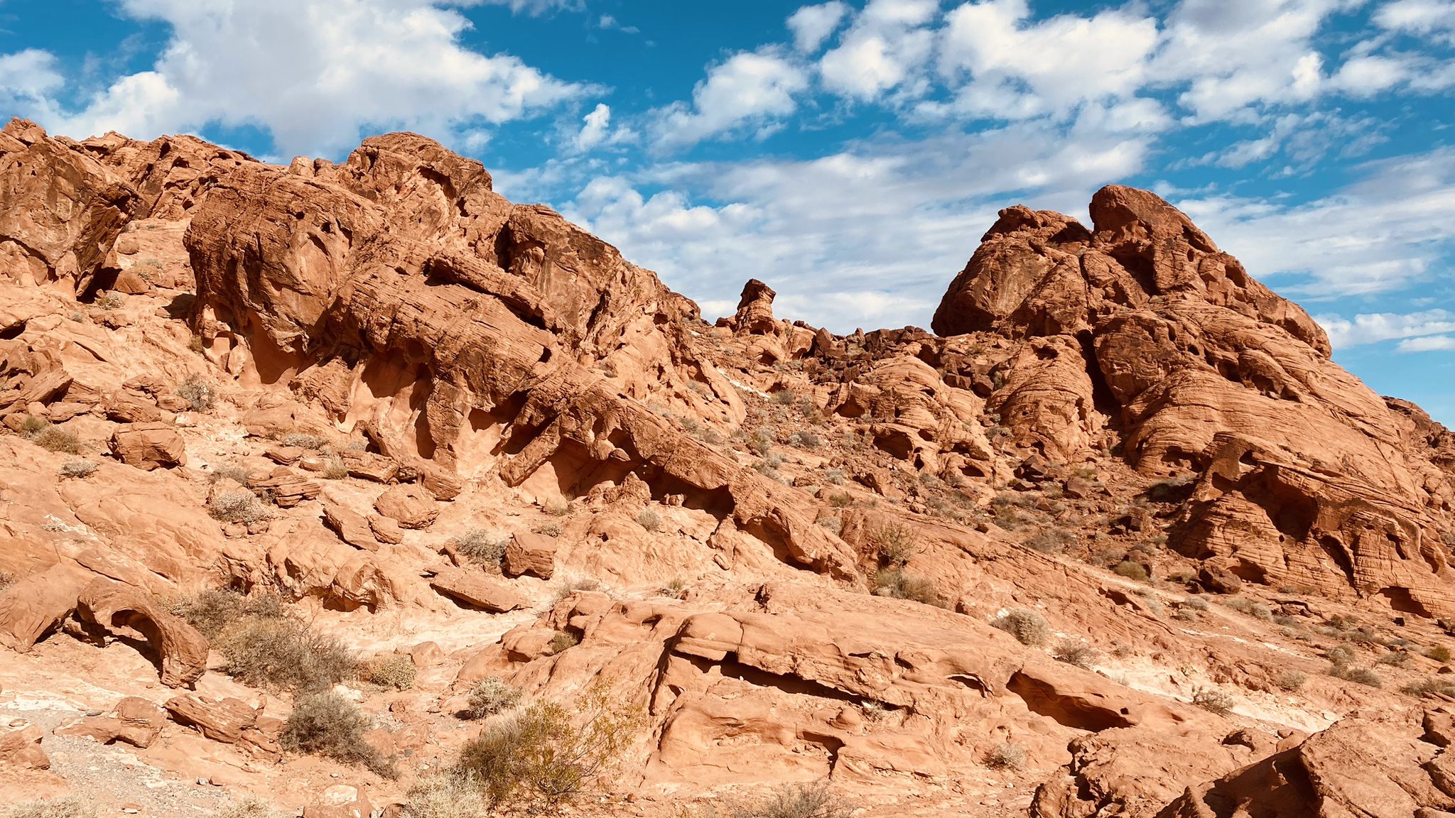 Rugged red rock formations dominate a desert landscape under a partly cloudy sky. - Elephant Rock Loop