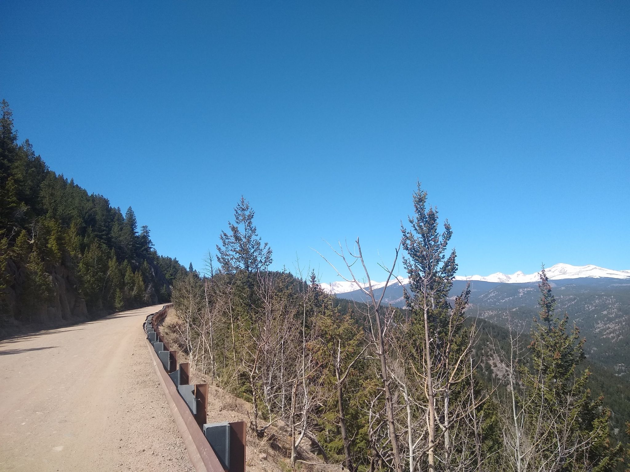 A dirt road winds along a hillside with distant snow-capped mountains. - Bald Mountain loop from Pine Brook Hill