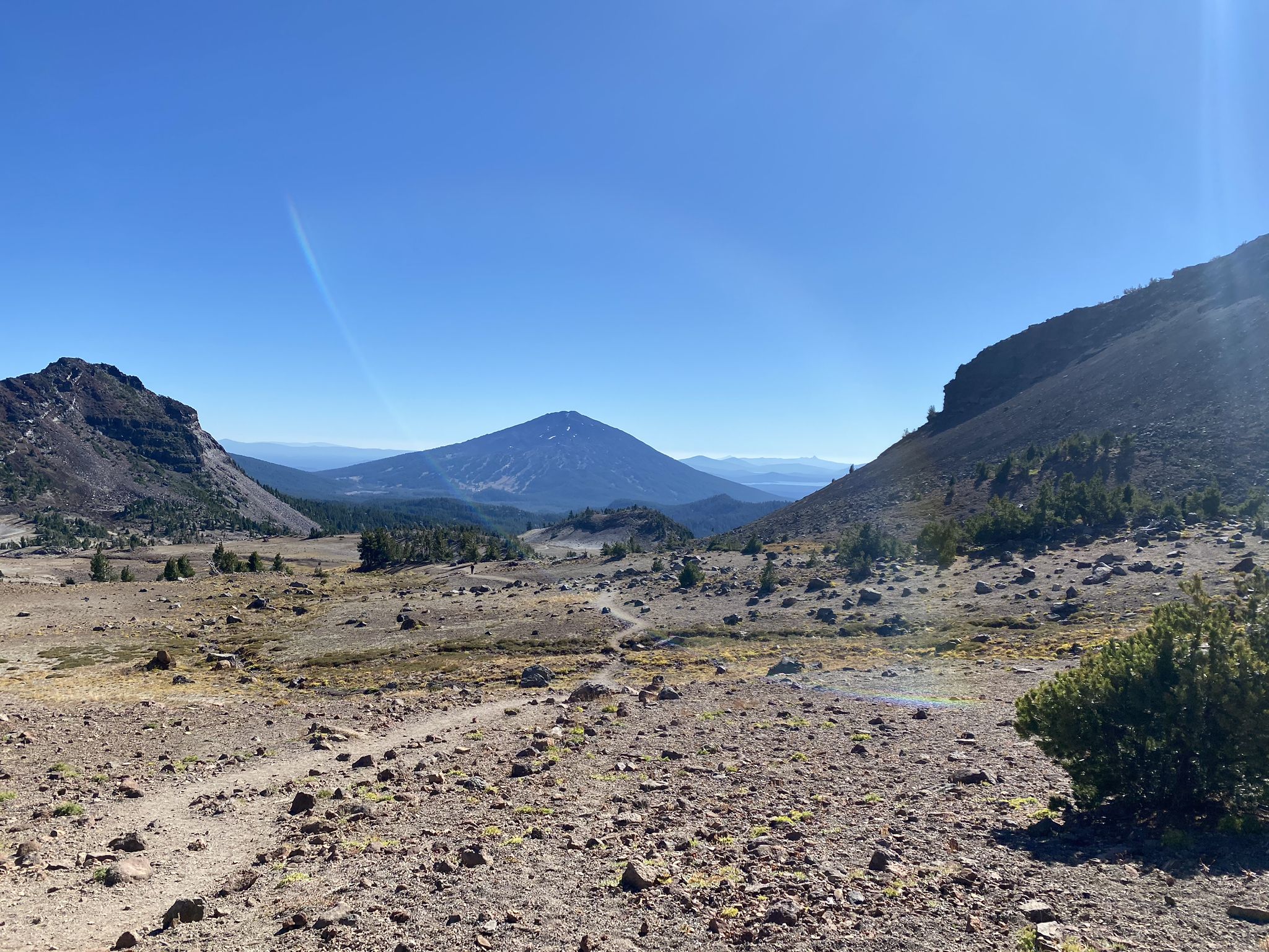 Rocky trail winding through a valley towards a distant mountain. - Broken Top Trail to No Name Lake