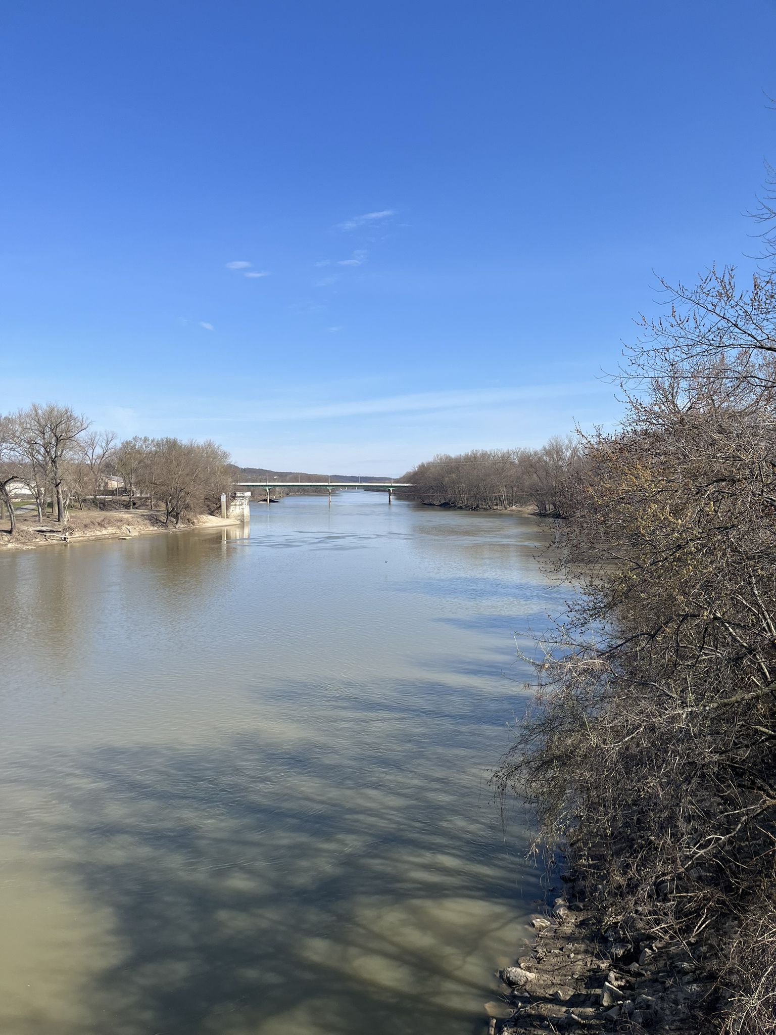 Wide river flowing under a distant bridge on a bright, clear day. - Wabash Heritage Trail