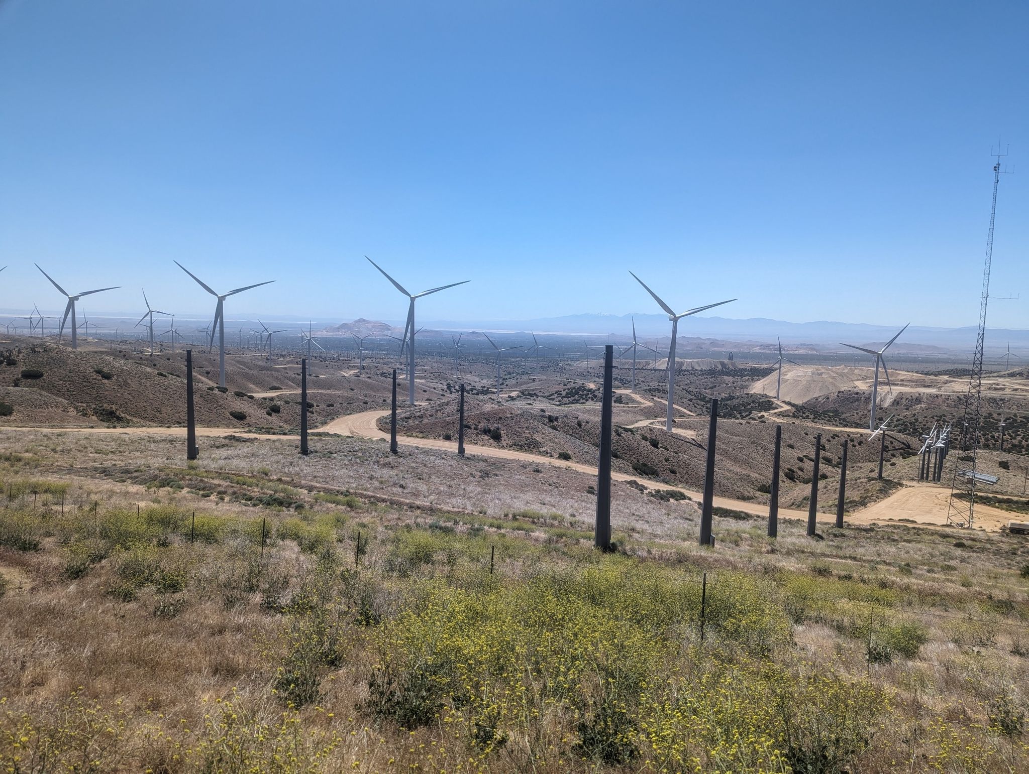 Numerous wind turbines and poles on dry, scrubby hills under a bright sky. - Pacific Crest National Scenic Trail