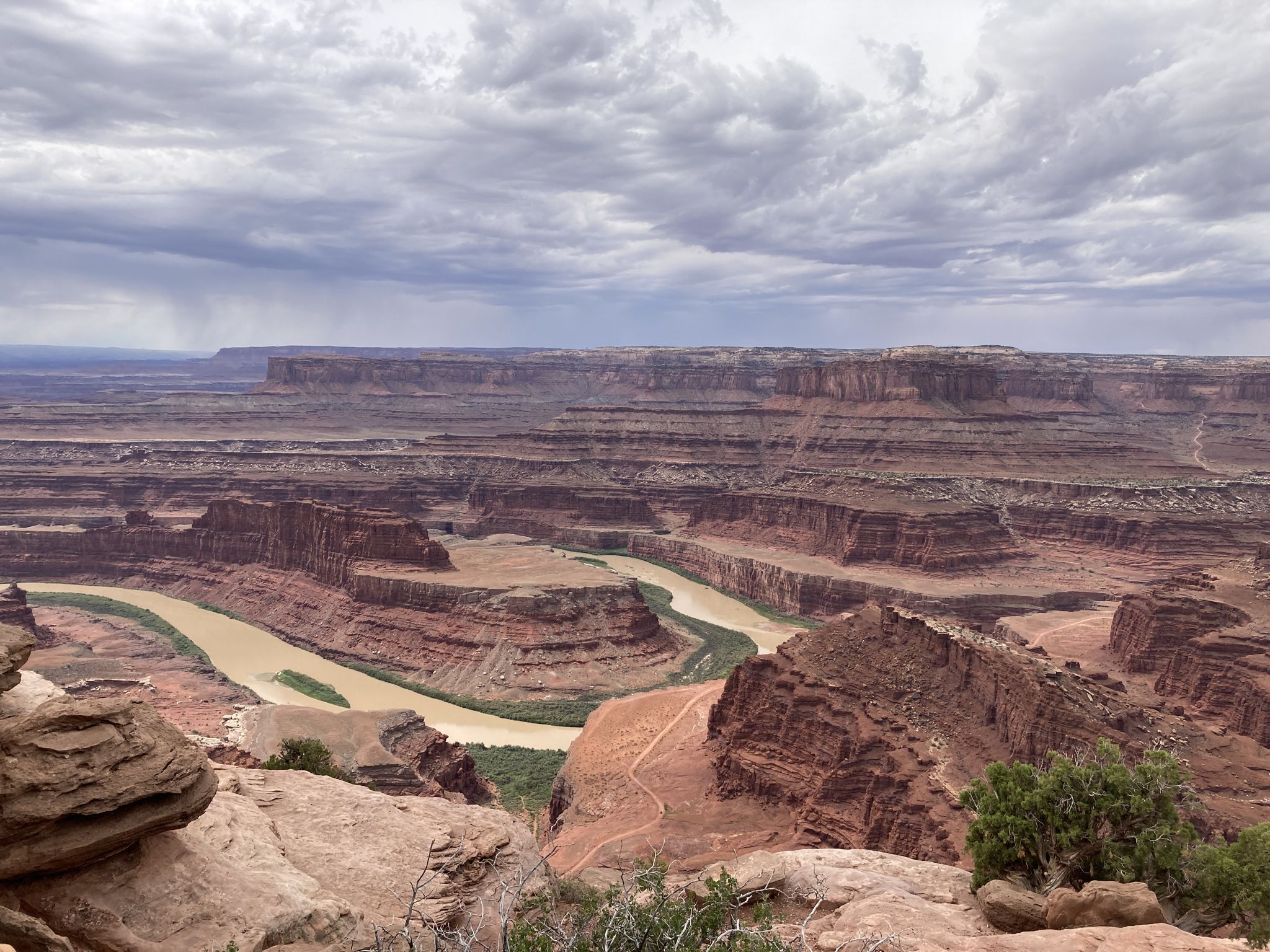Wide canyon with a winding river under a dramatic cloudy sky. - East and West Rim Loop