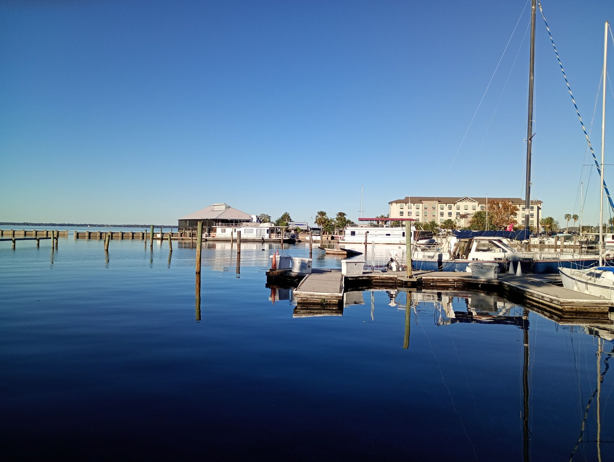Sunny marina scene with boats, docks, and buildings reflecting in calm water. - Veterans Memorial Park Sanford – Monroe Marina loop from Sanford