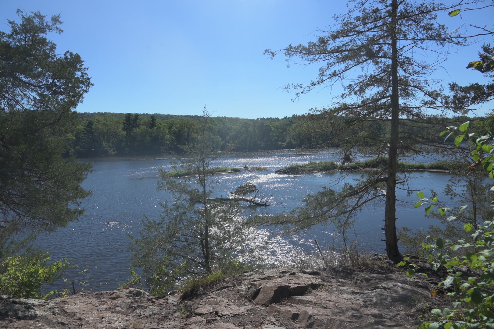 Sunny river with small islands, viewed from a rocky cliff, clear sky. - Railroad and Walter F. Mondale River Trail Loop