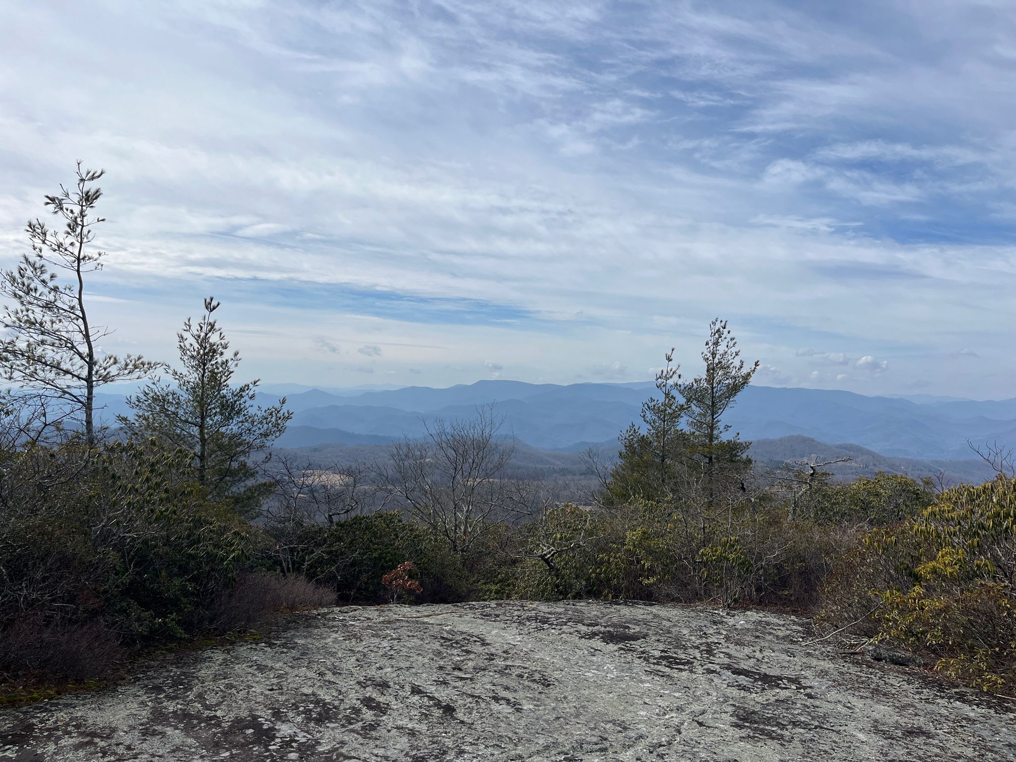 Rocky overlook with distant blue mountains under a partly cloudy sky. - Bartram Trail and Jones Knob Loop