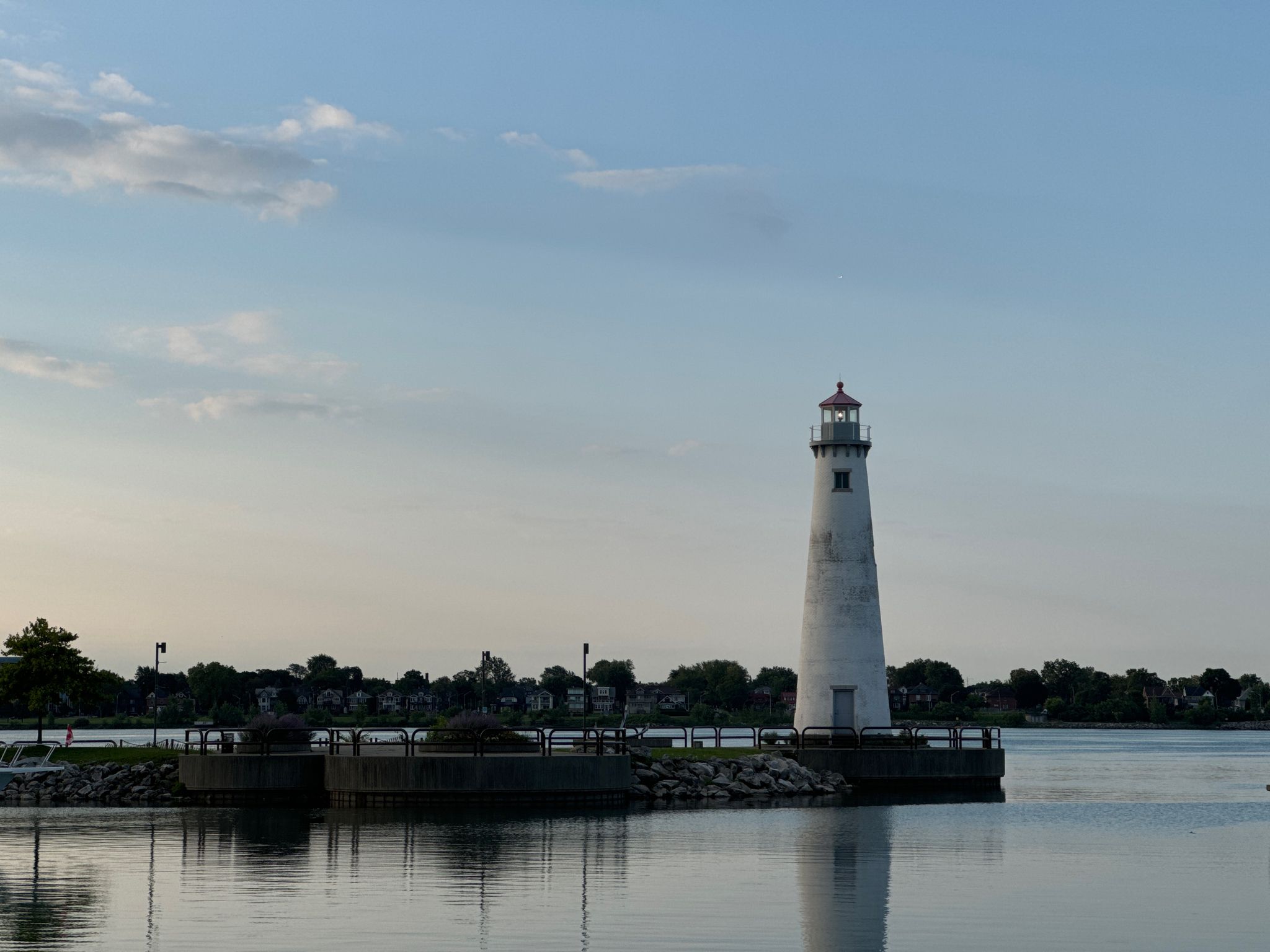 White lighthouse on a pier in calm water under a soft evening sky. - Rivertown District – Detroit Riverwalk Viewpoint loop from Lafayette Park